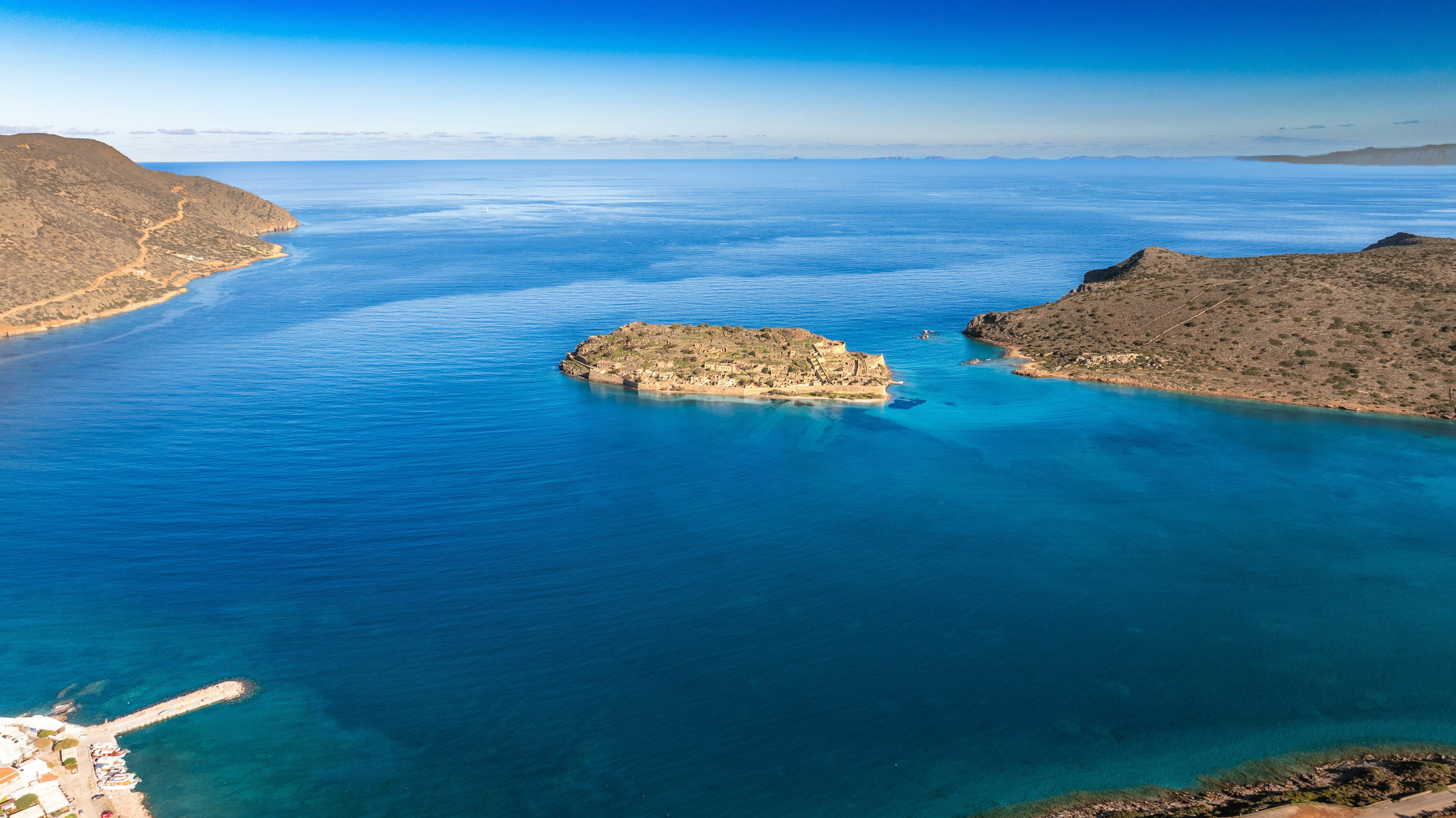 Island in a bright blue bay with rocky shores.