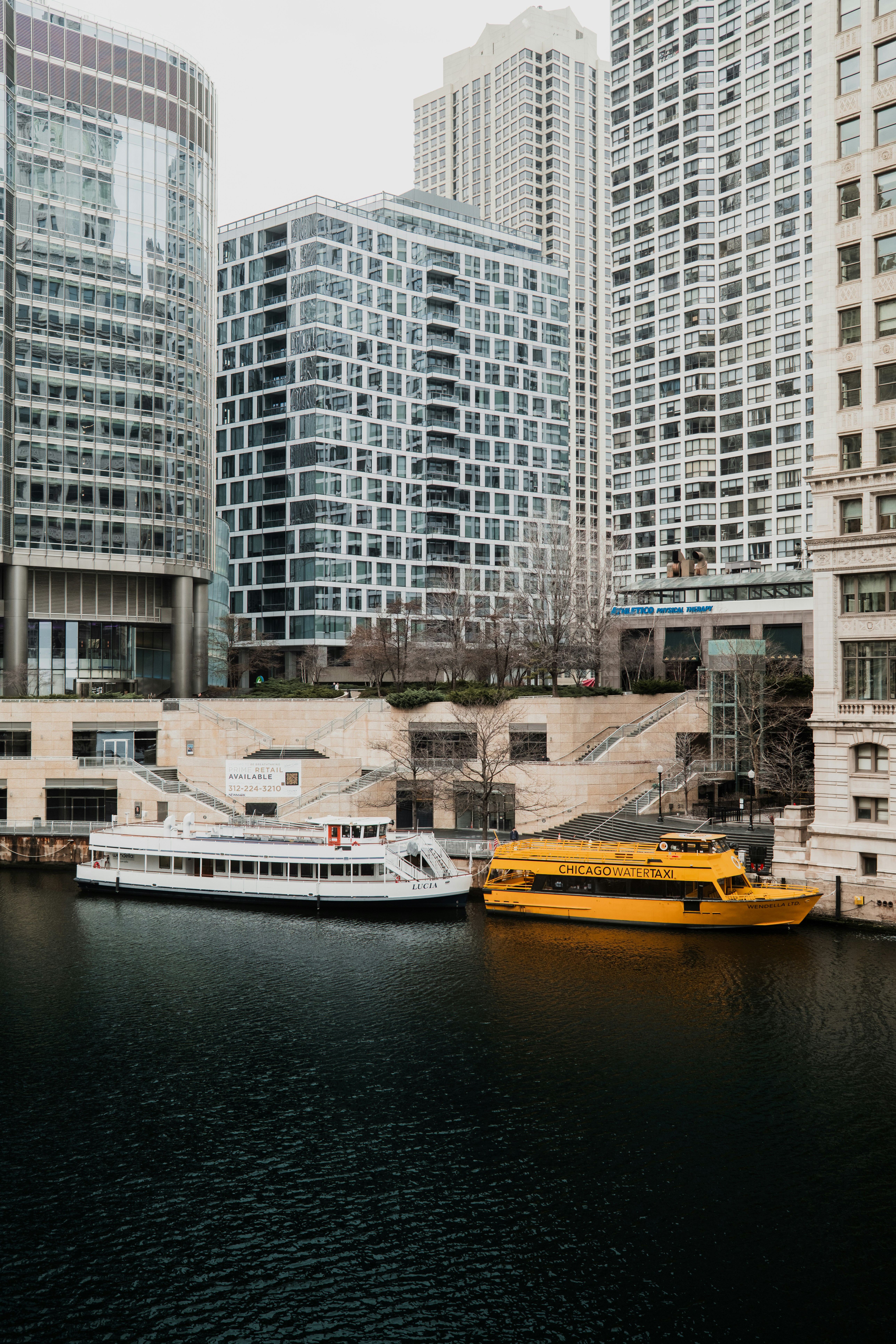 Two boats docked on a river next to buildings