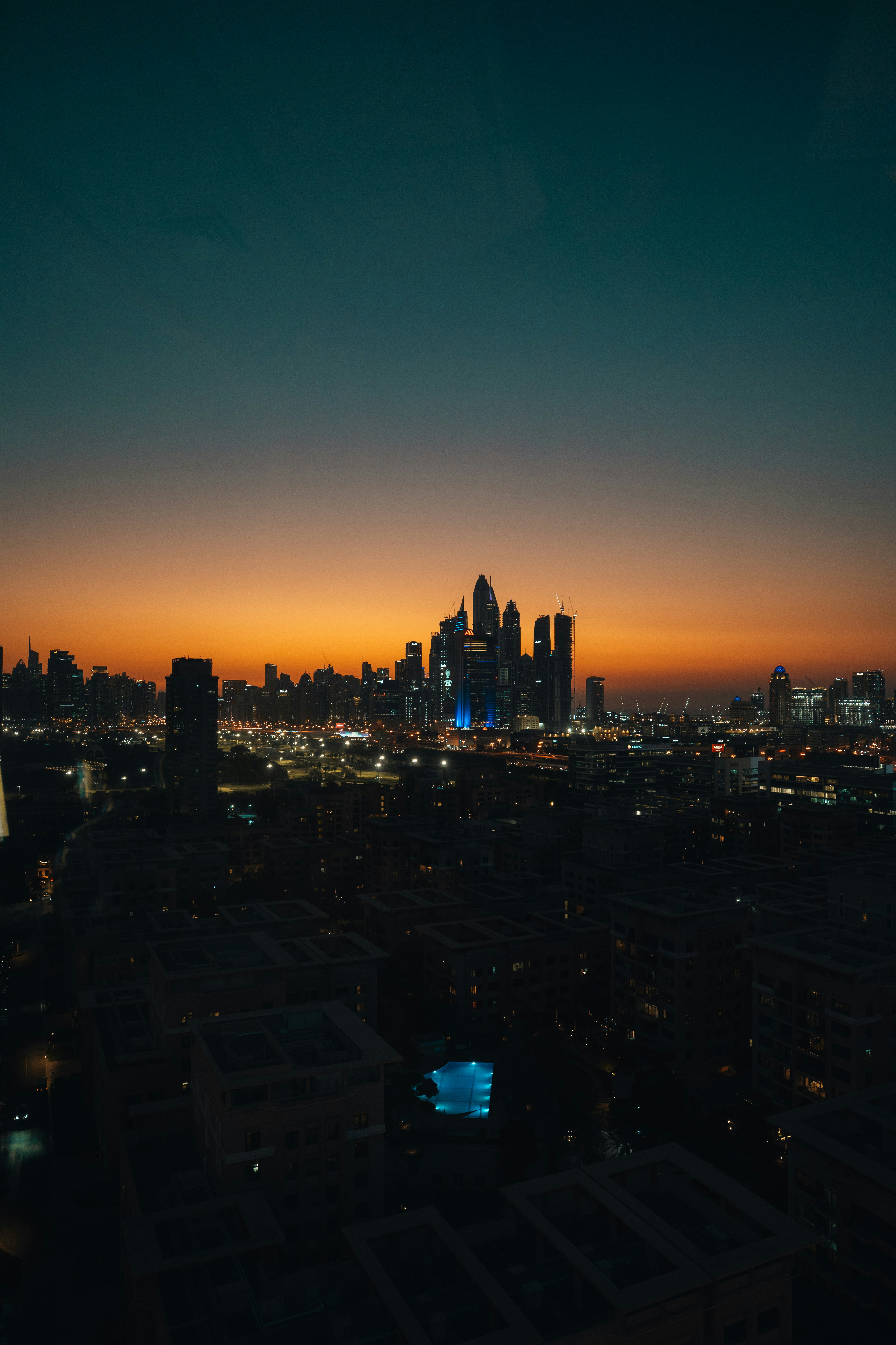 City skyline illuminated at dusk with colorful sky.