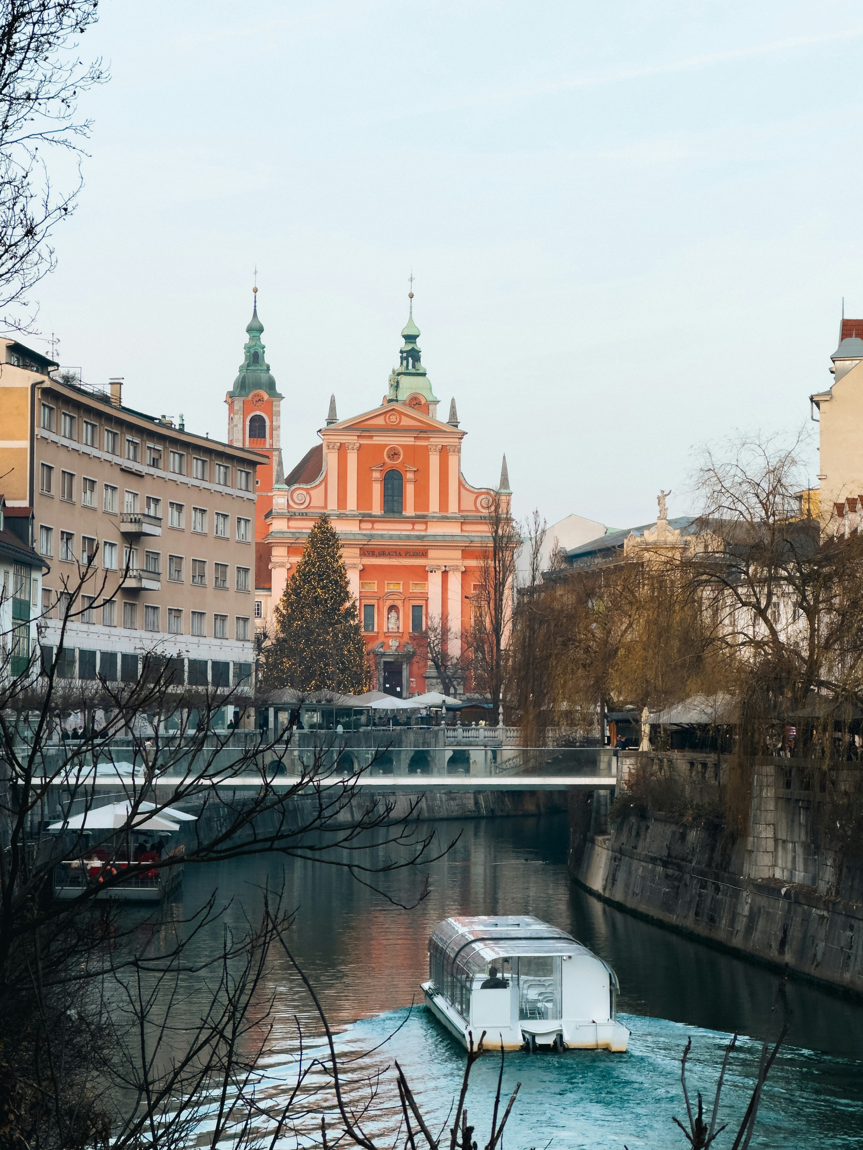 Boat on river with church and buildings in background.