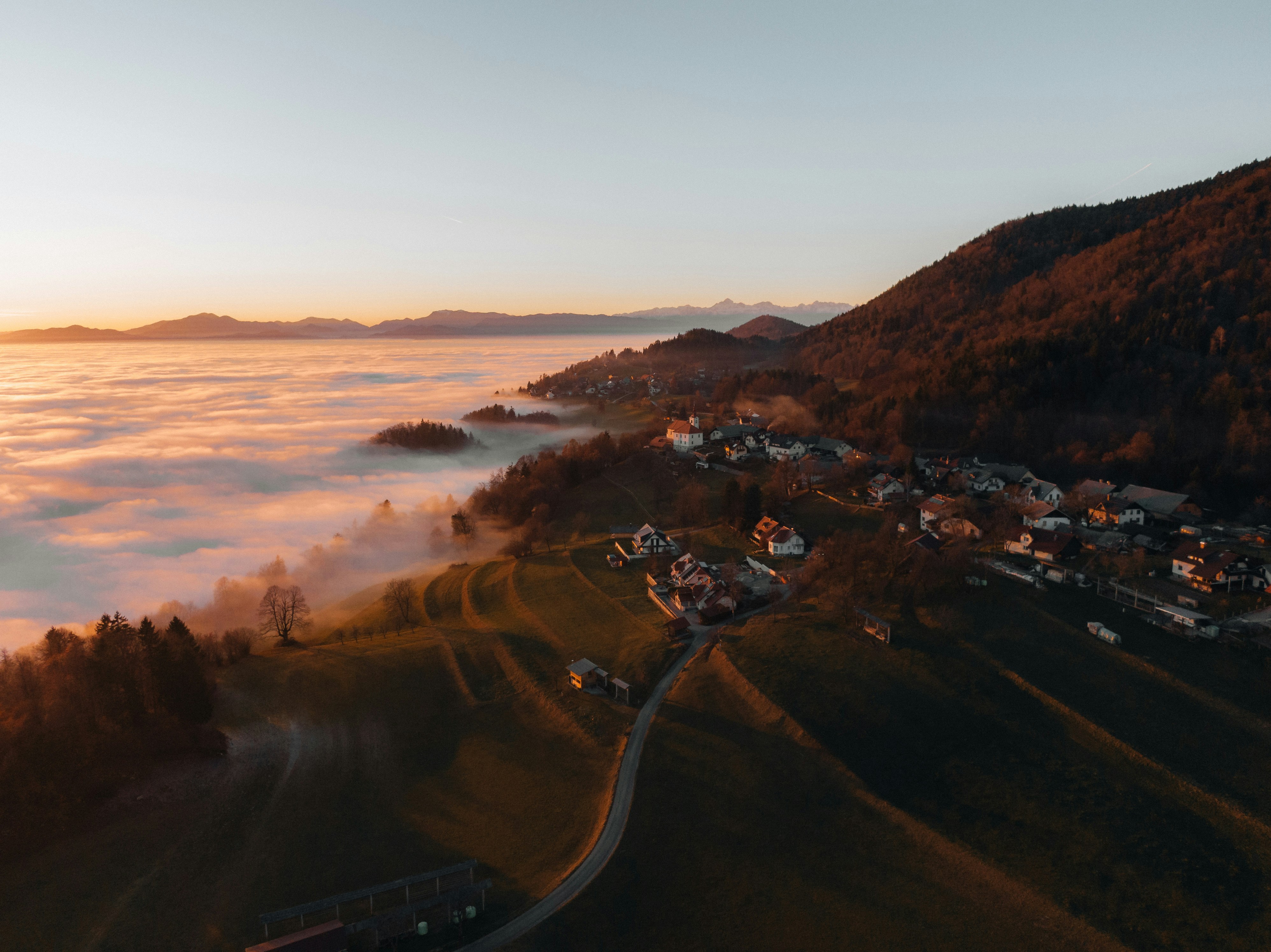 Aerial view of village nestled in misty hills at sunrise