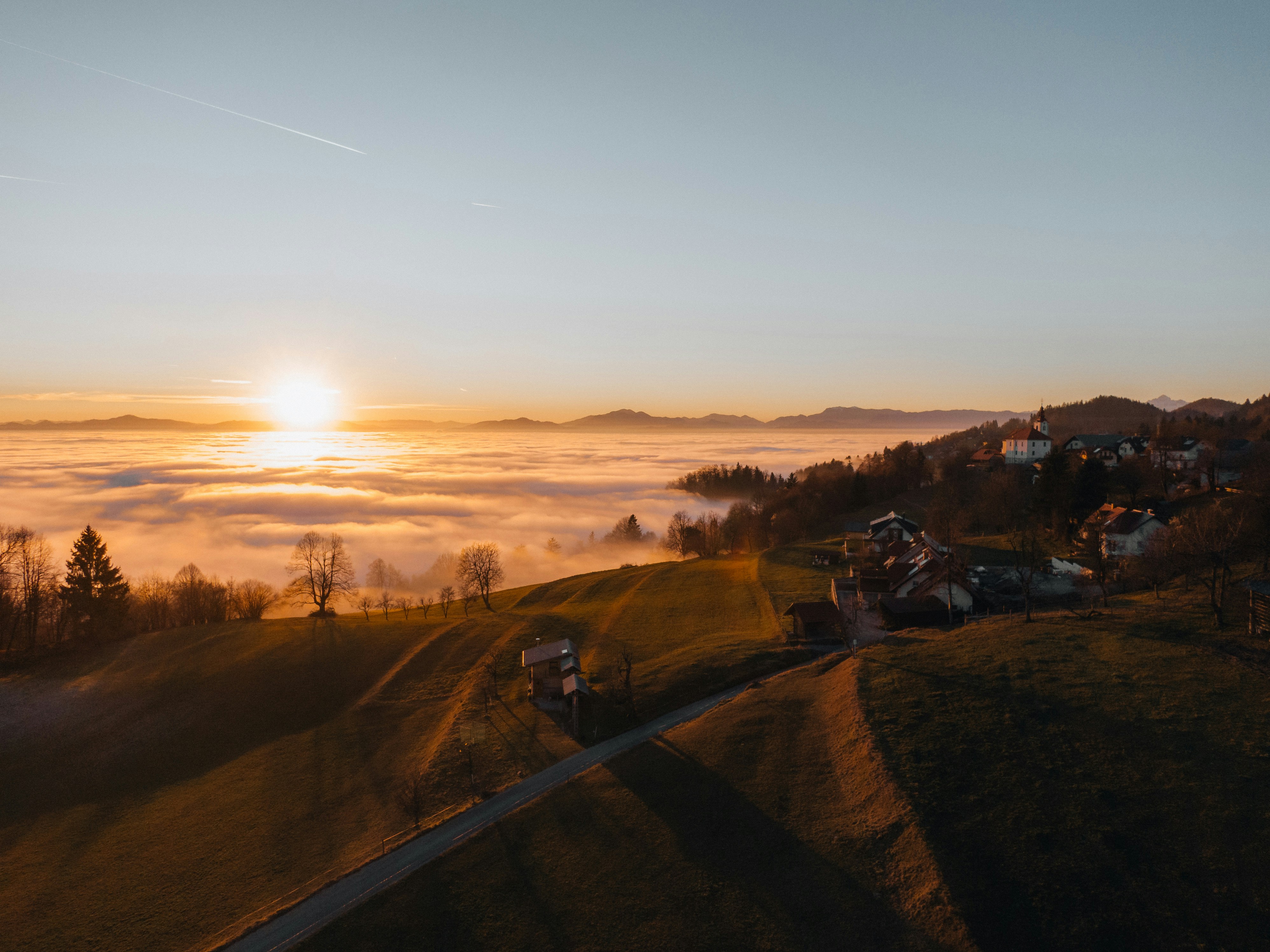 Sunrise over a misty valley with rolling hills.