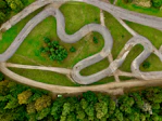 Aerial view of a winding asphalt track through green grass.