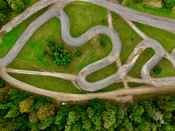Aerial view of a winding asphalt track through green grass.