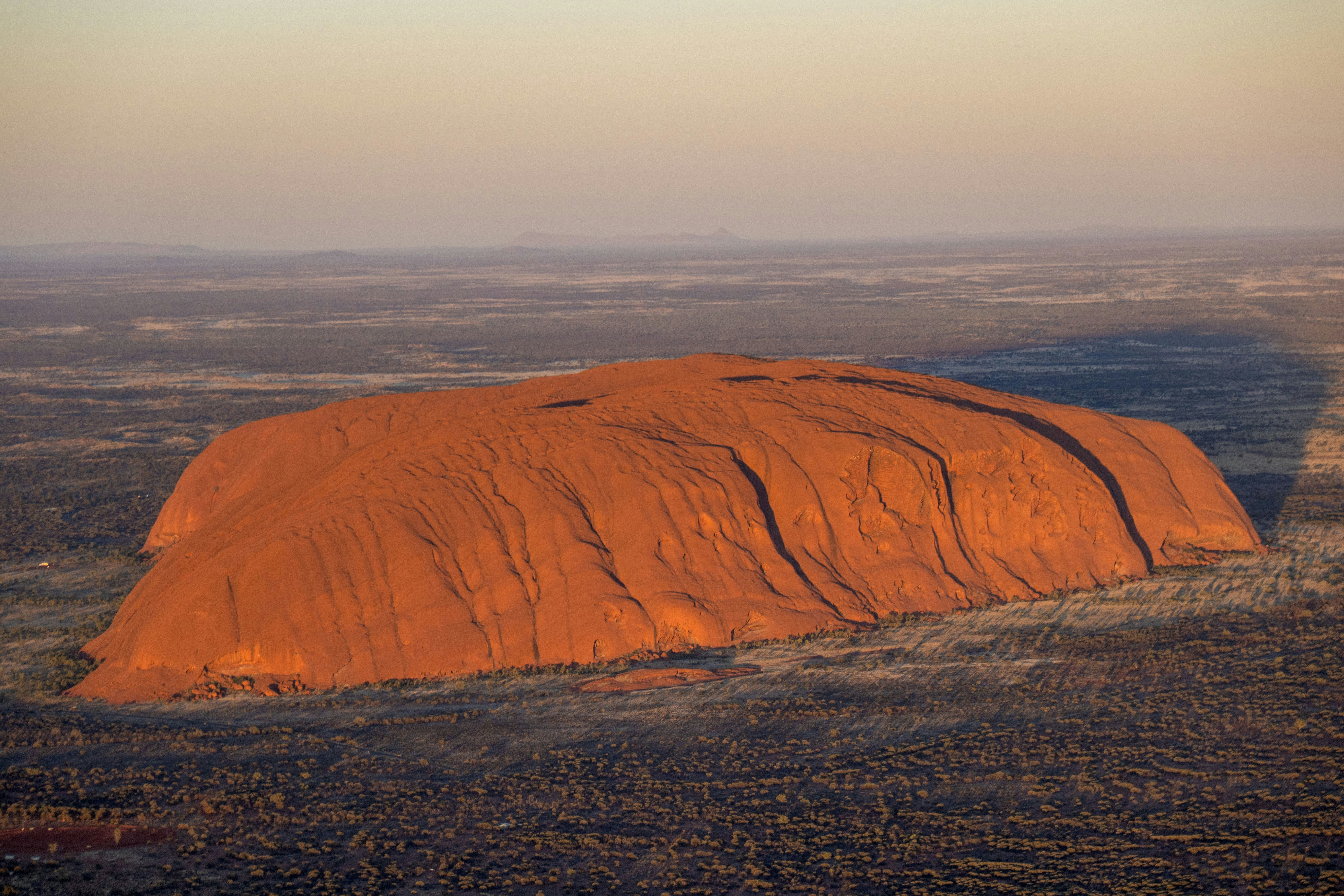 Uluru rock formation in the australian outback at sunset.