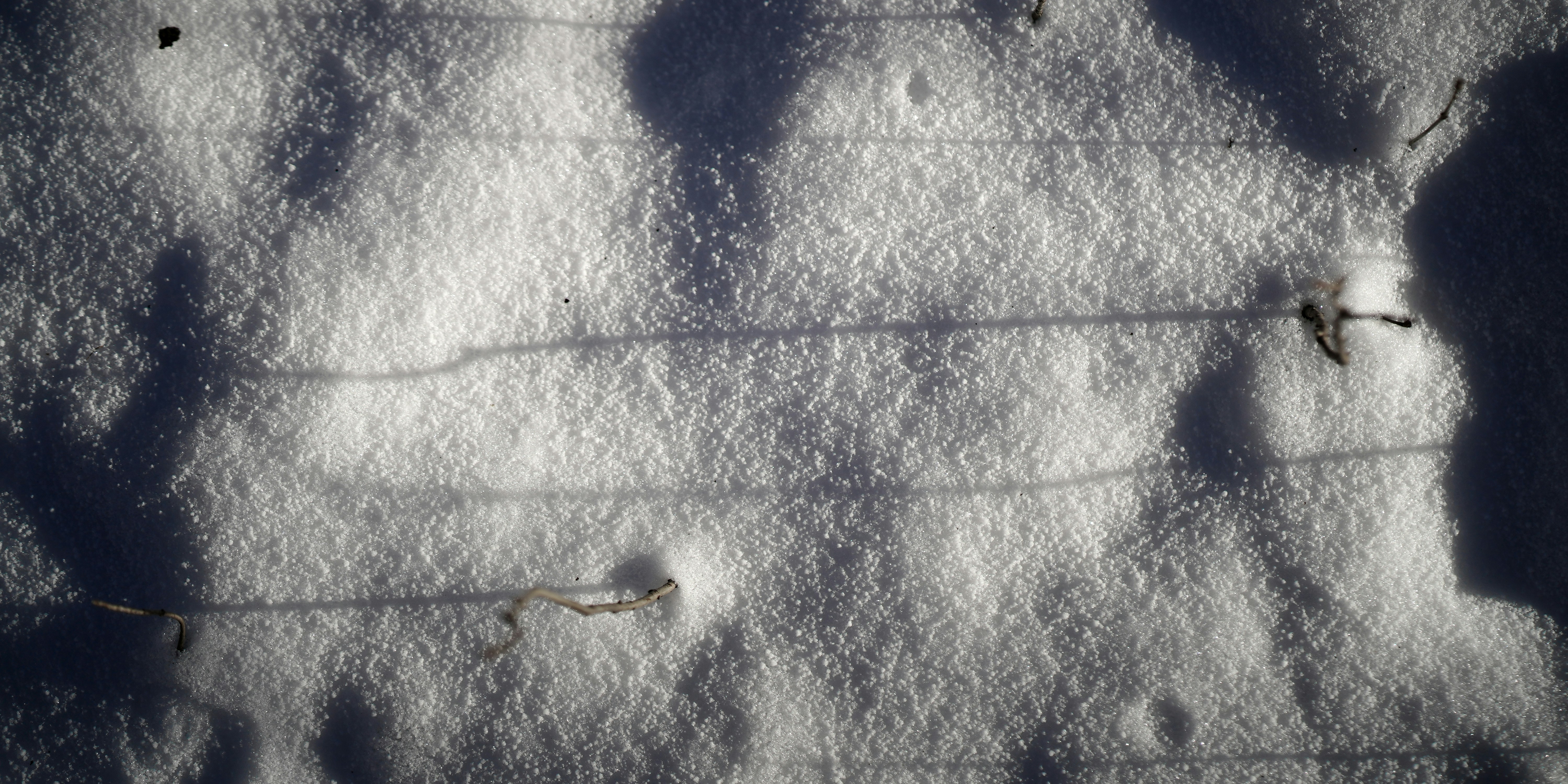 Close-up of snow with horizontal lines and shadows.