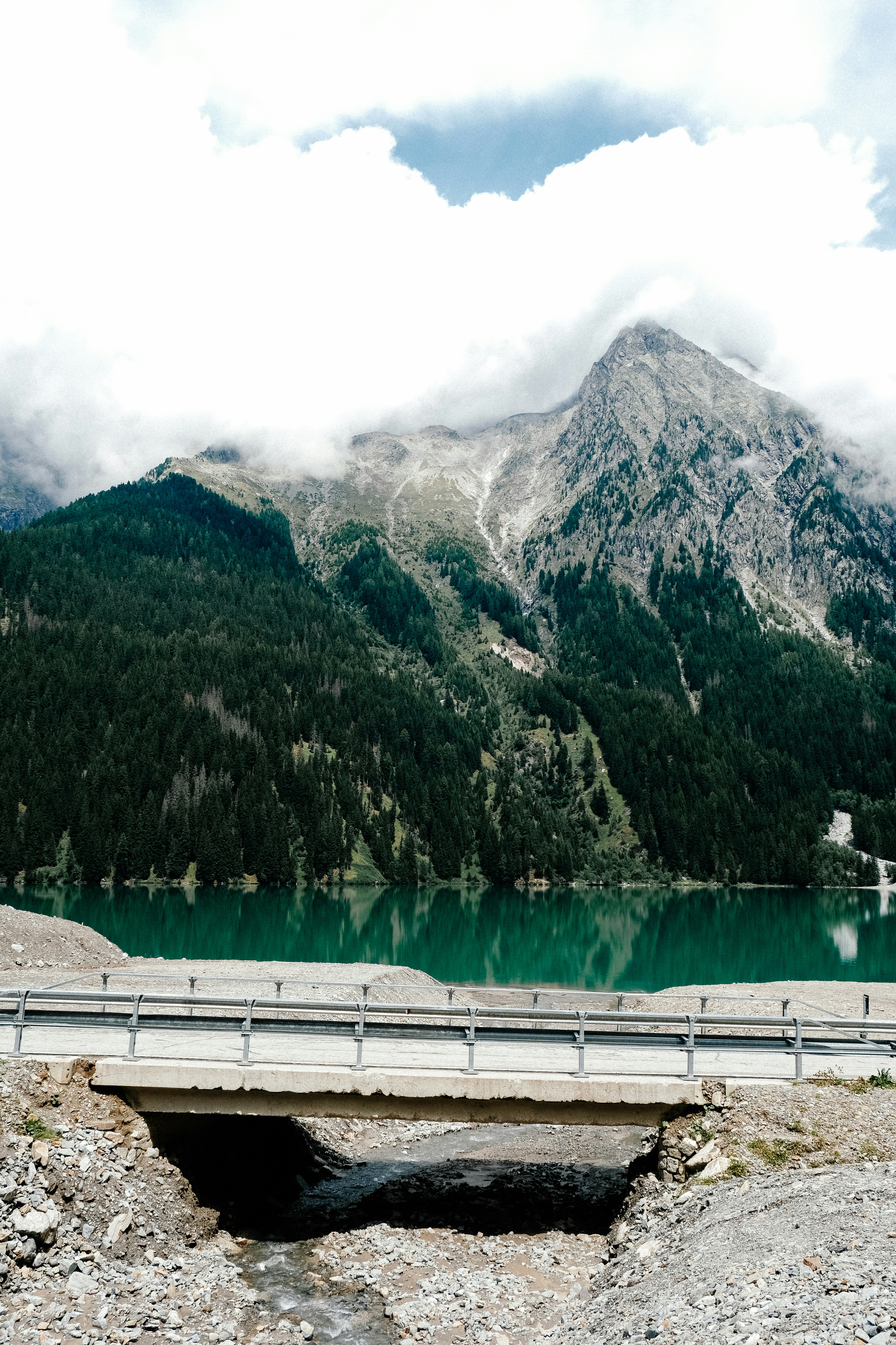 A bridge over a stream with a lake and mountain.