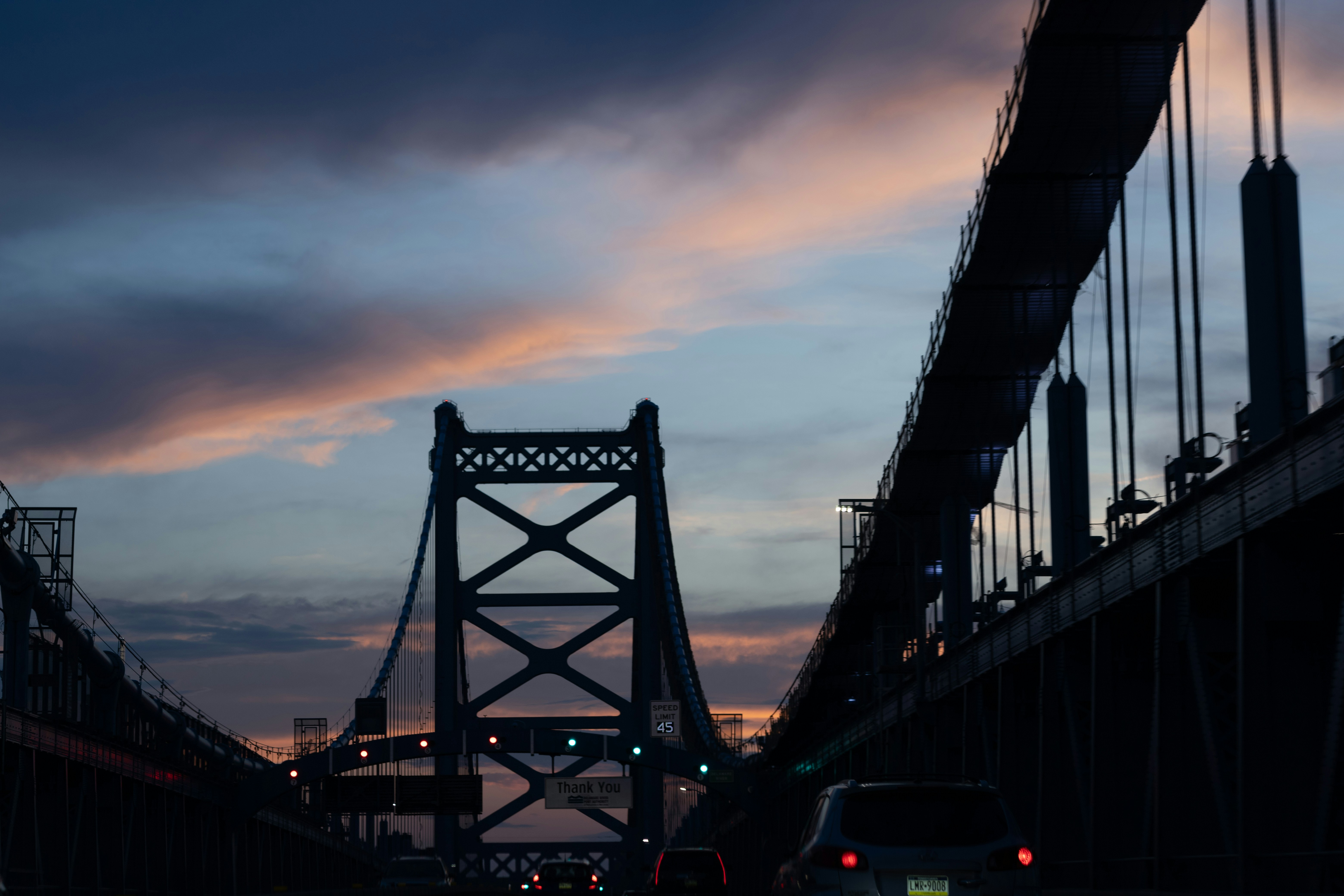 Suspension bridge at dusk with dramatic clouds