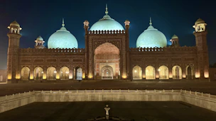 A grand mosque illuminated at night with glowing domes.