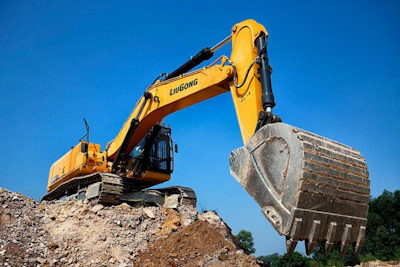 Yellow excavator digging dirt against a blue sky
