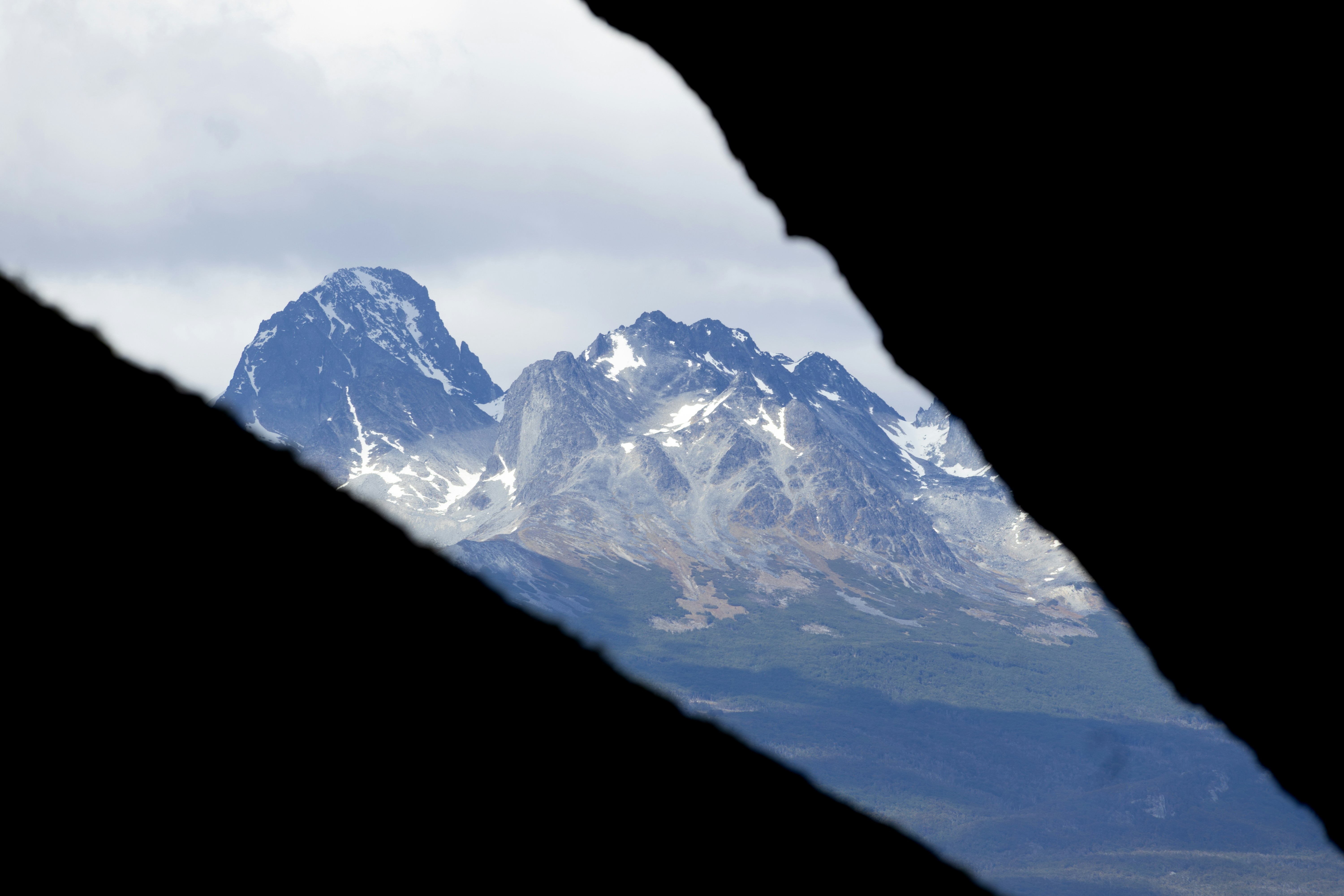 Snow-capped mountains seen through a dark opening