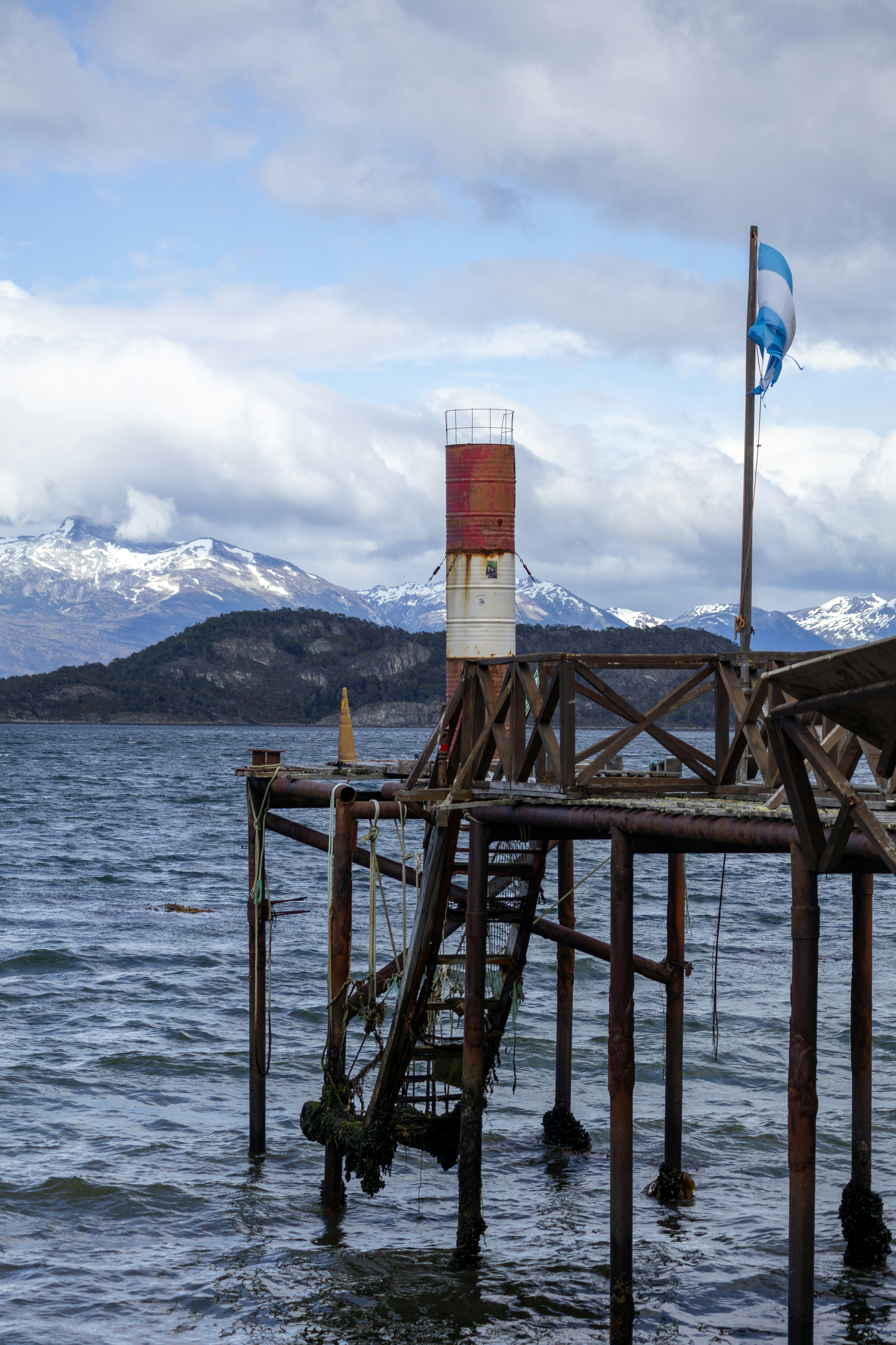 Rustic pier with lighthouse and flag by the water