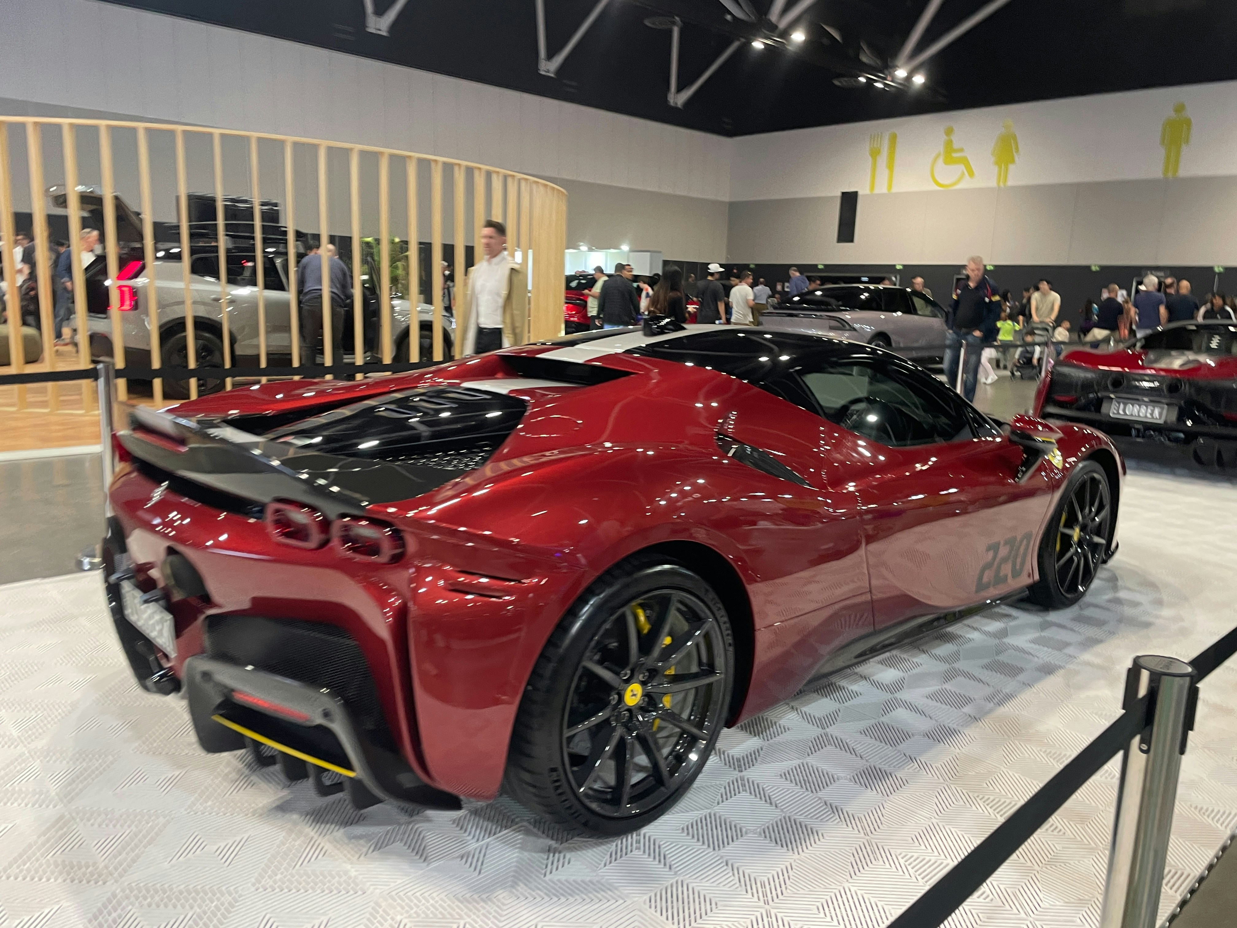 A red sports car on display at an auto show.
