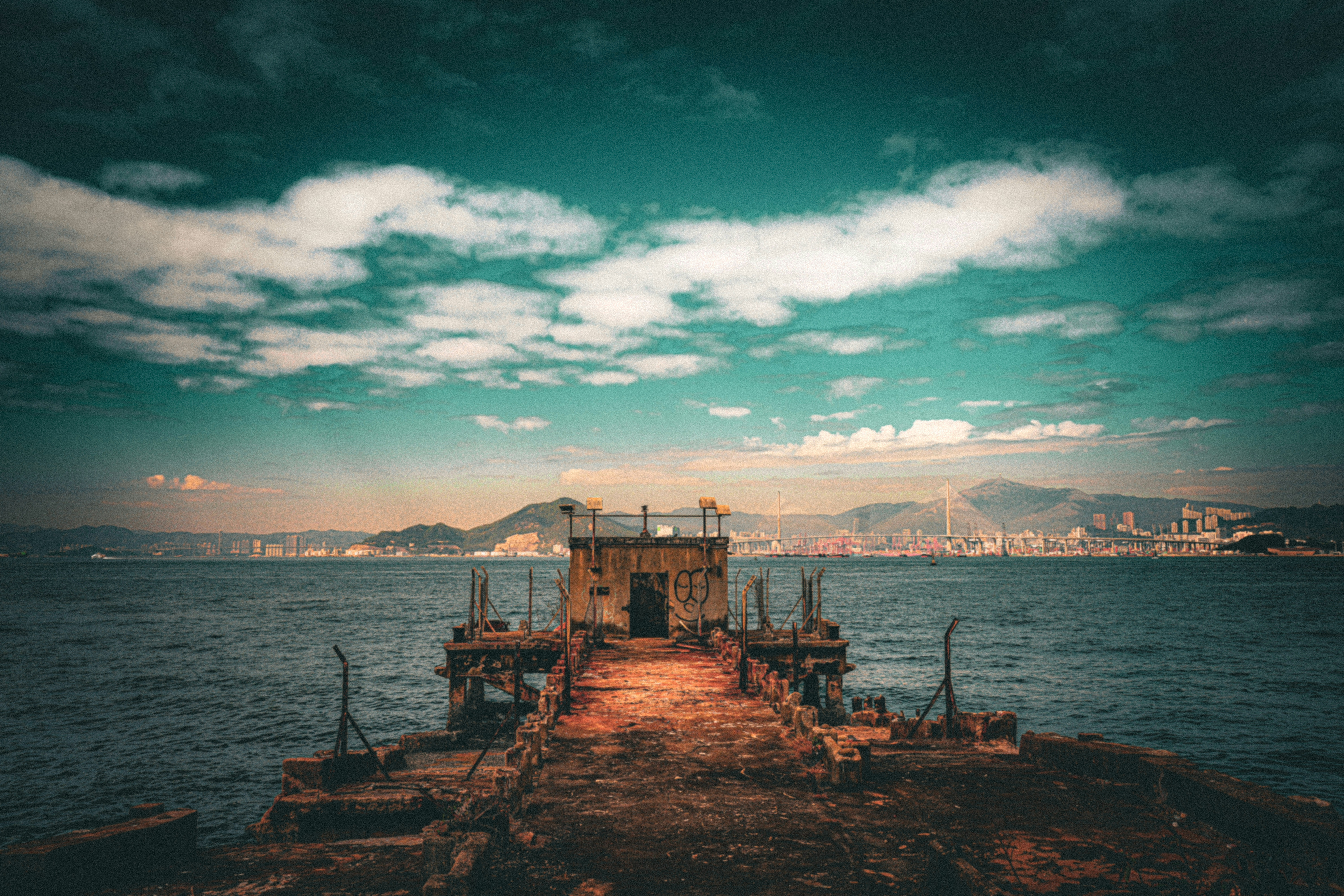 Abandoned pier leading to a distant city skyline