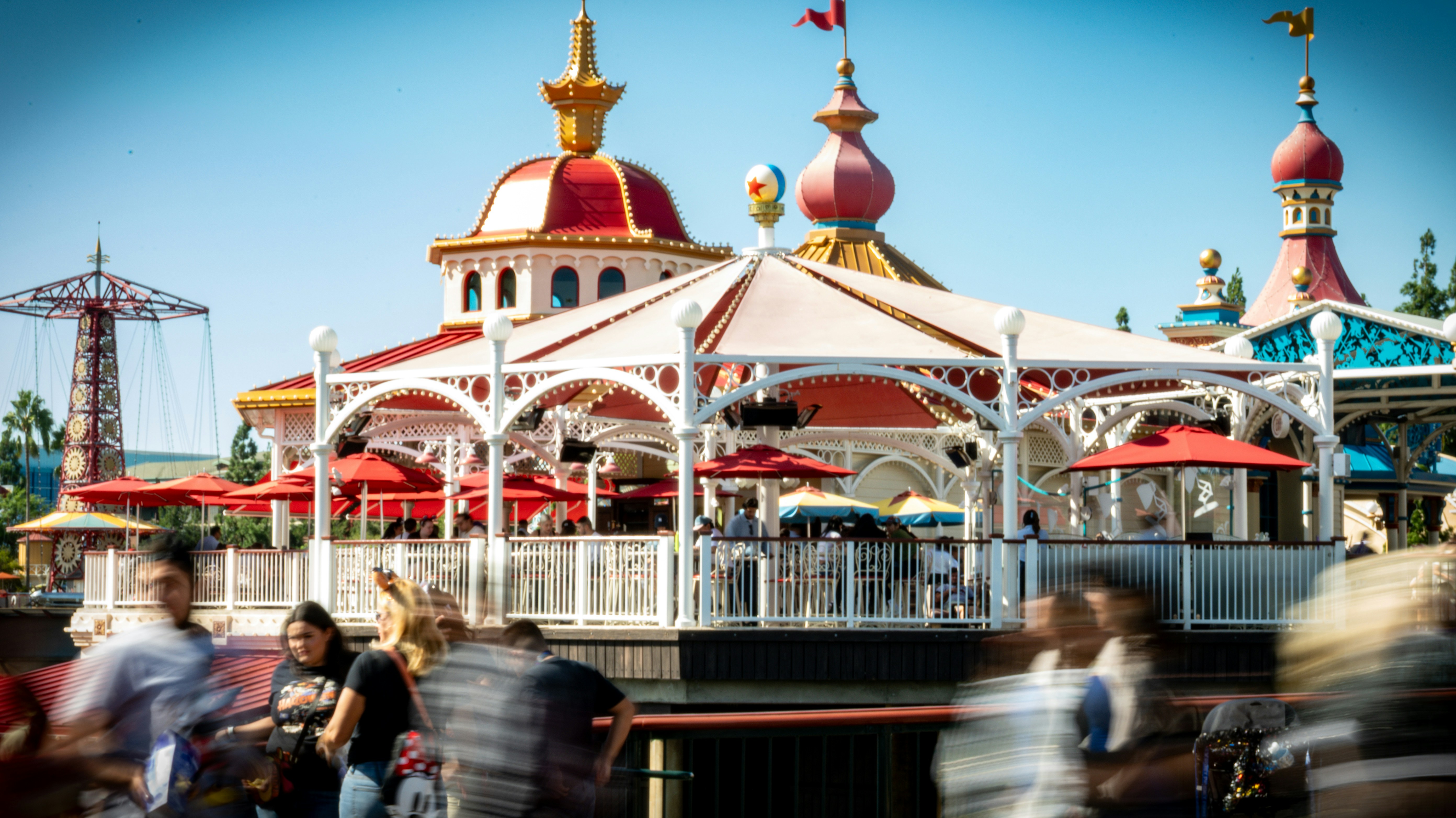 People walk past a colorful building at a theme park.