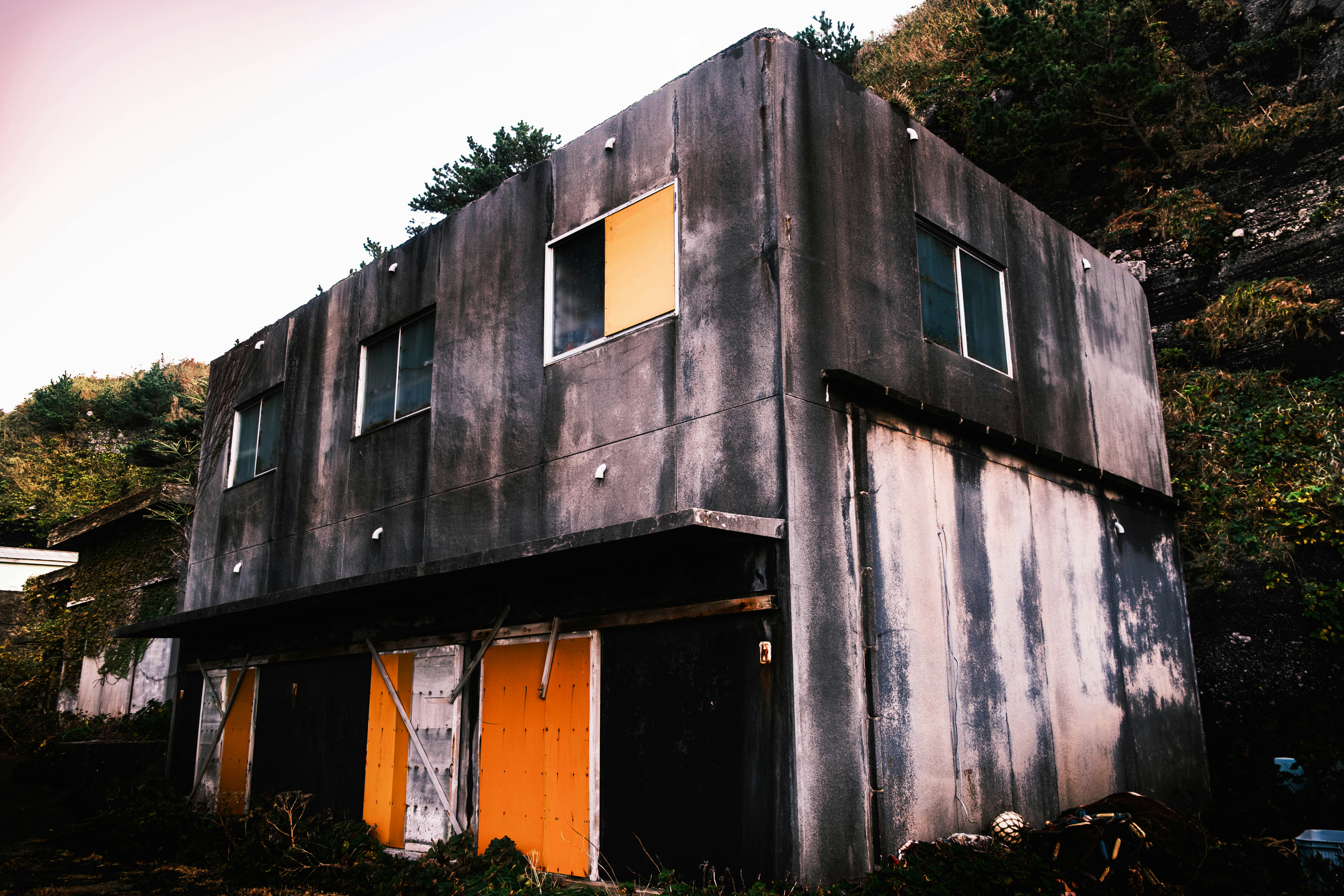 Abandoned concrete building with orange doors and yellow accents.