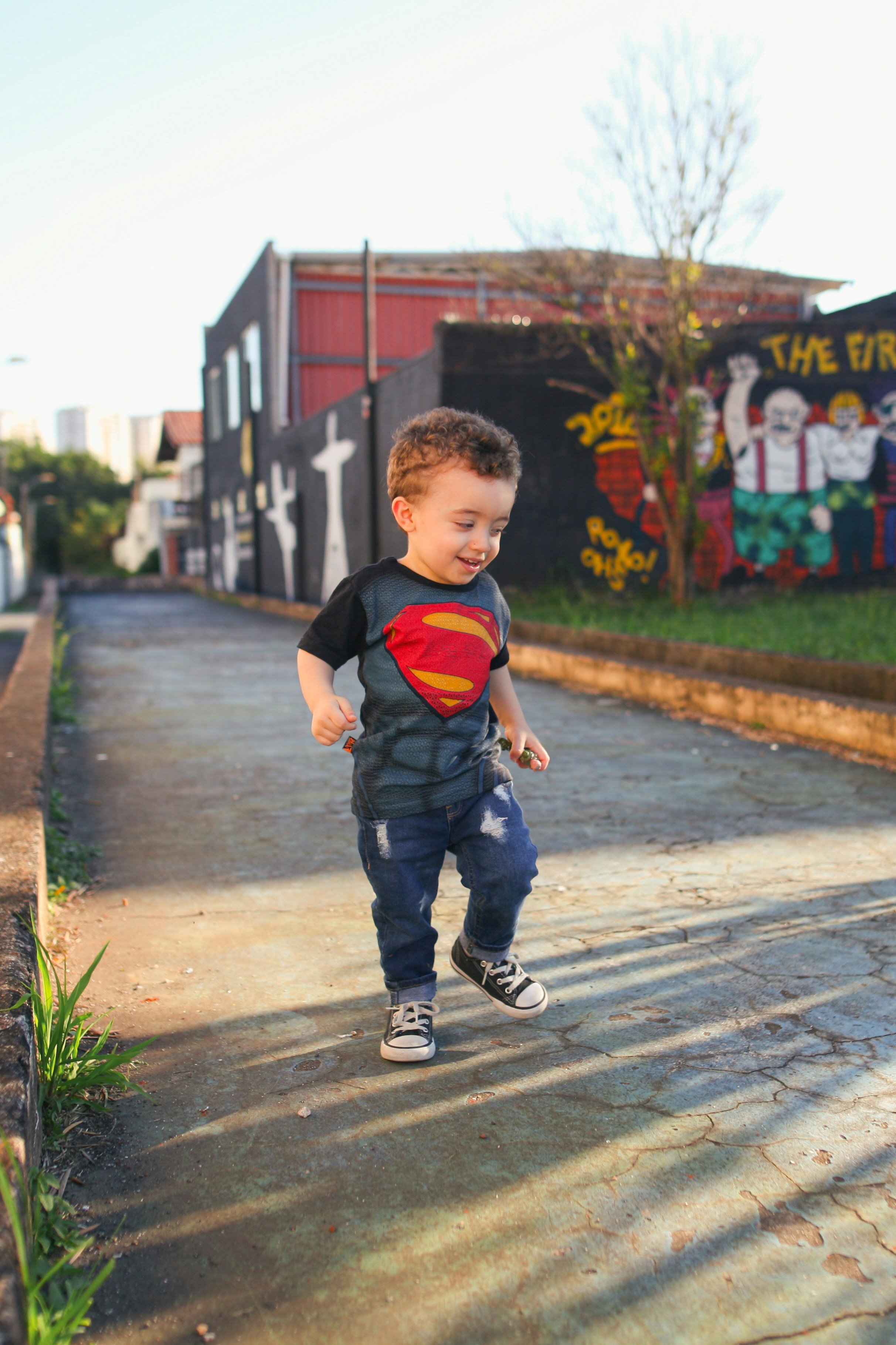 Young boy in superman shirt walks outside