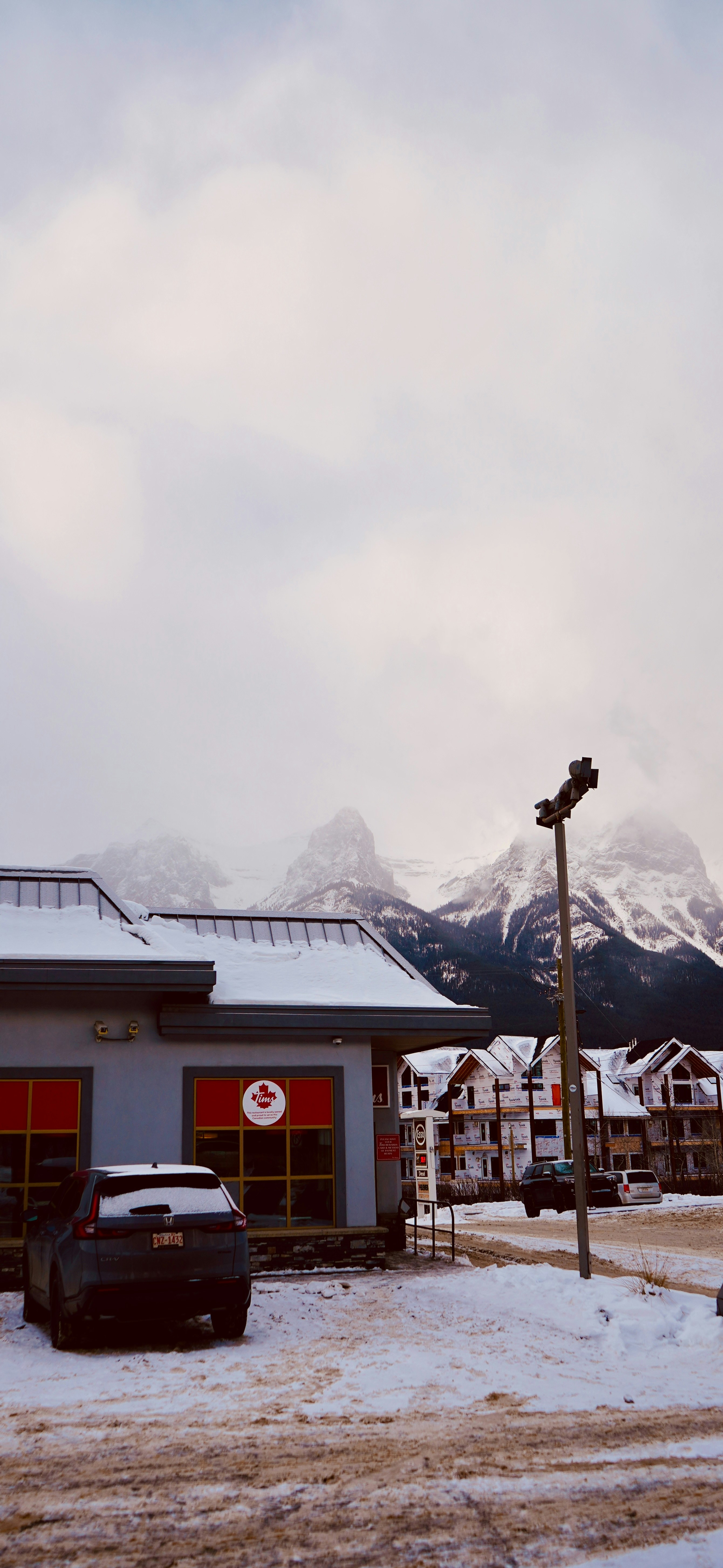 Schneebedeckte Berge hinter einem Gebäude und Auto.