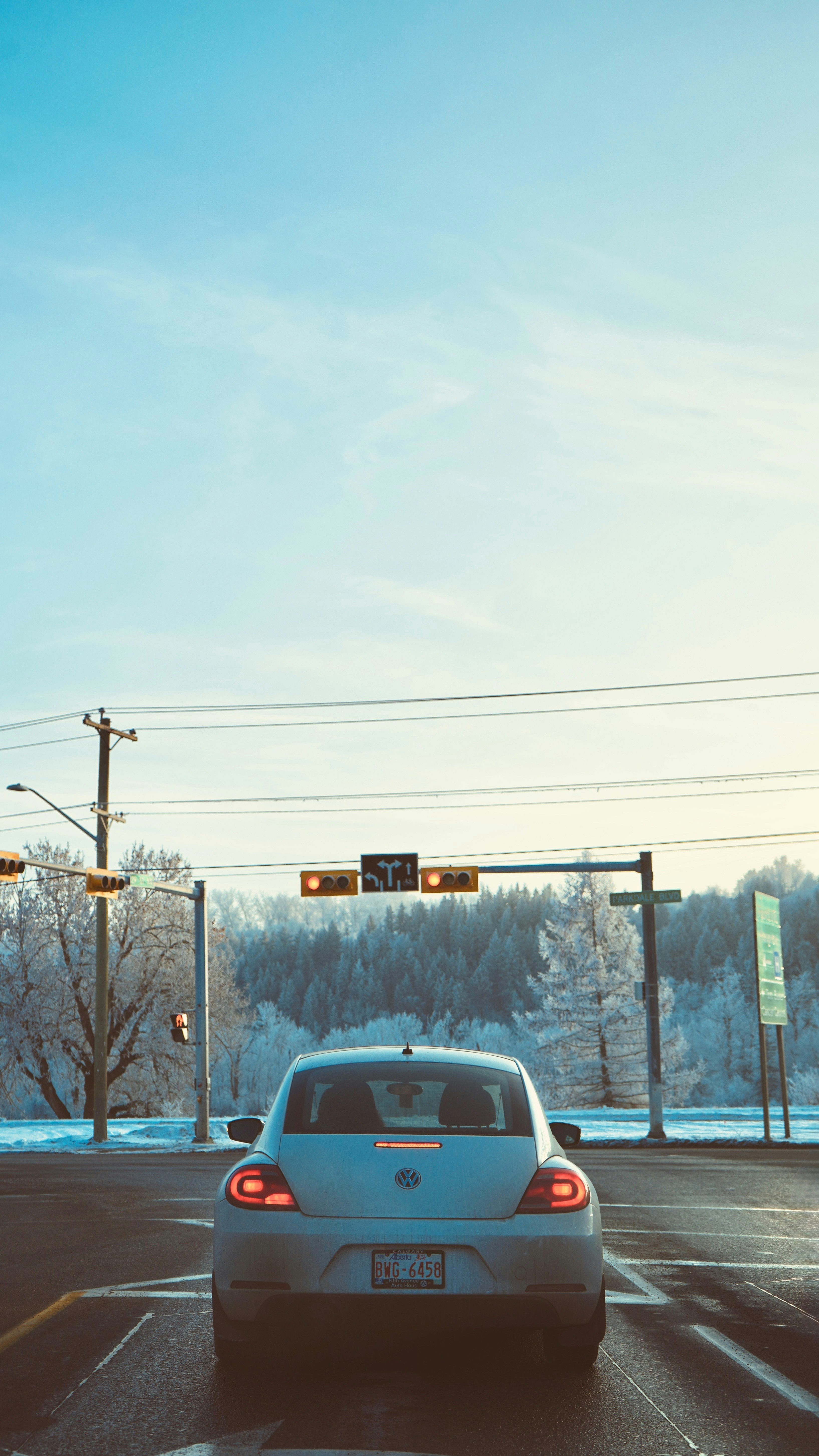Weißes Auto wartet an einer Winterampel.