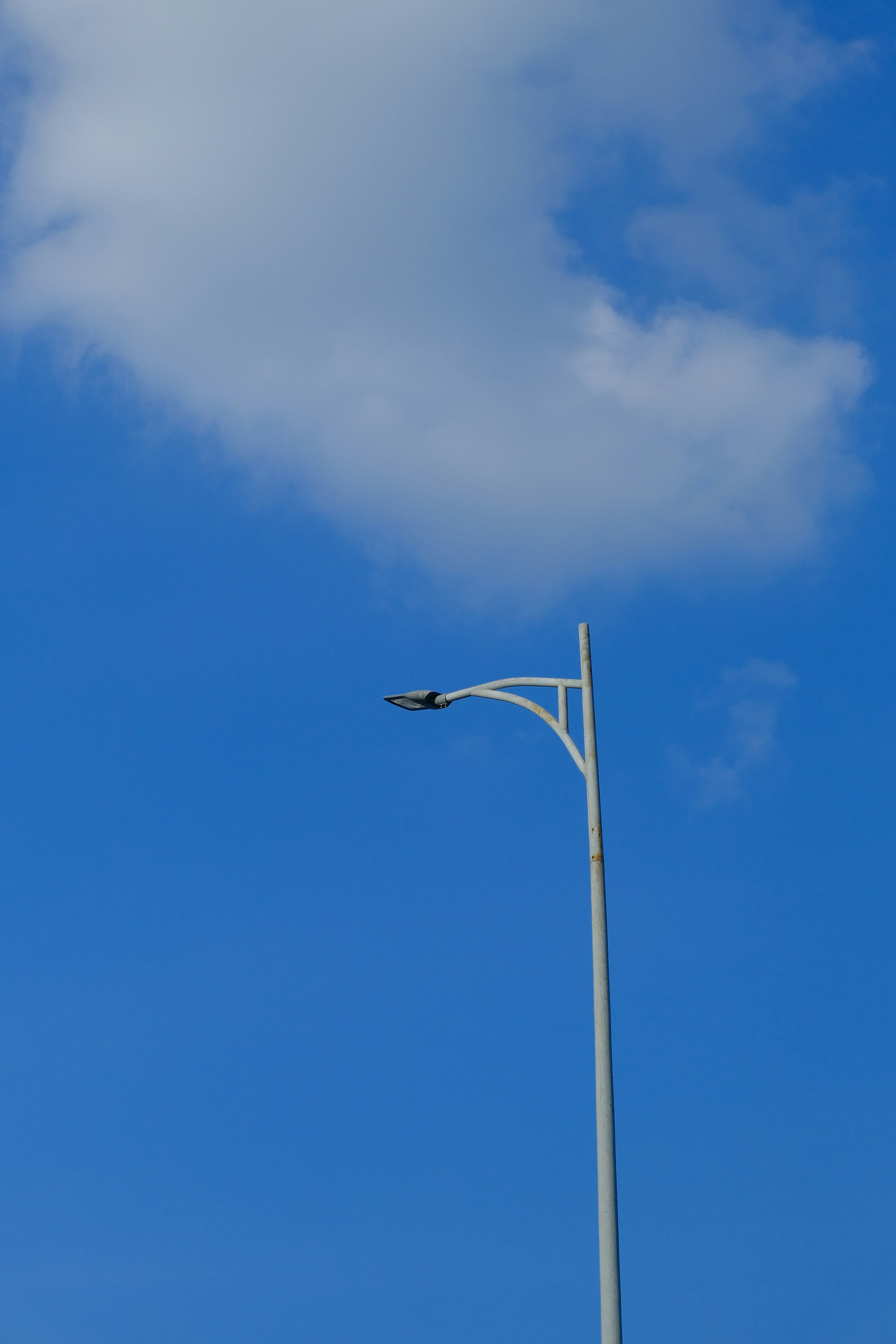 A modern street lamp against a bright blue sky.