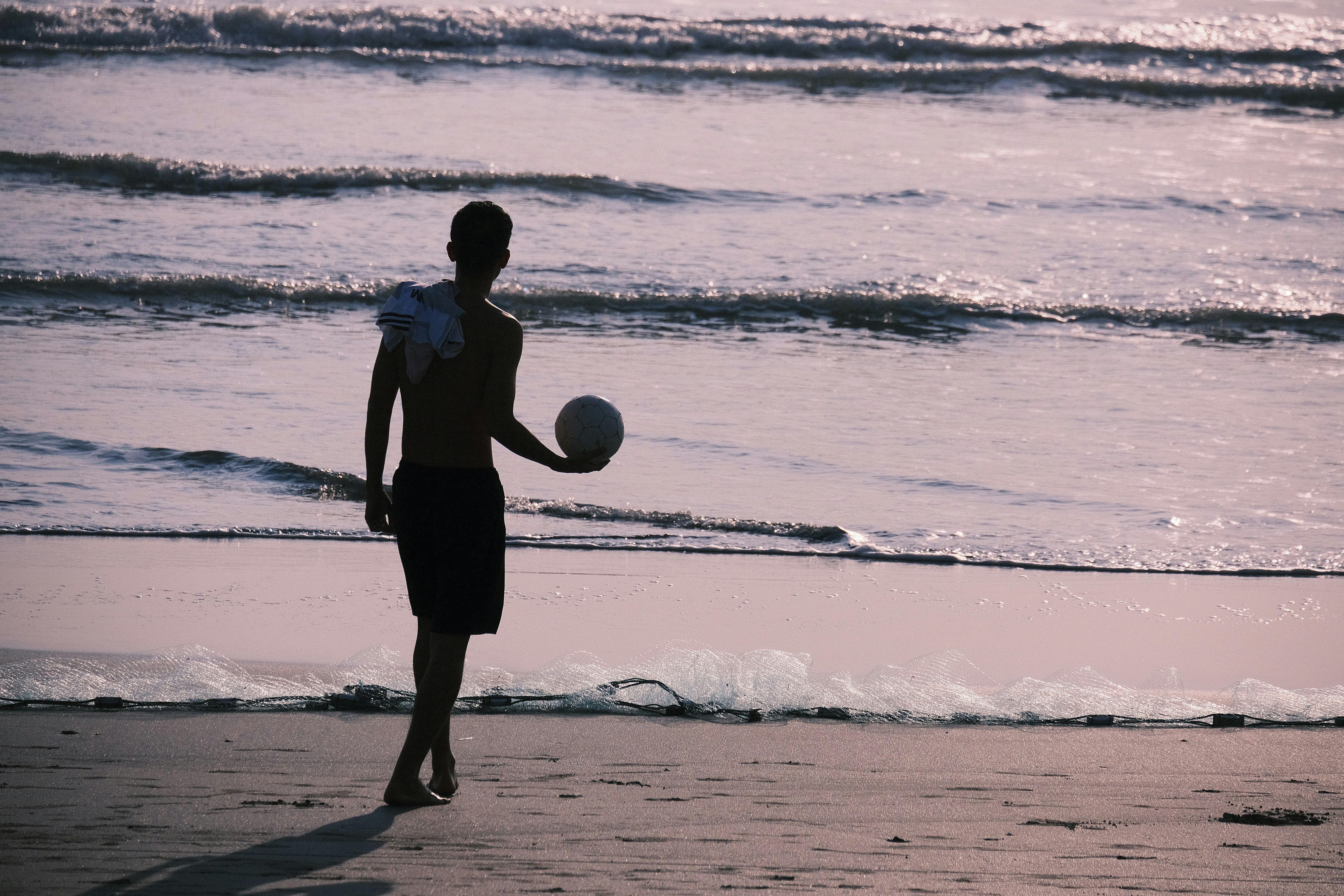 Man walking on beach holding a volleyball