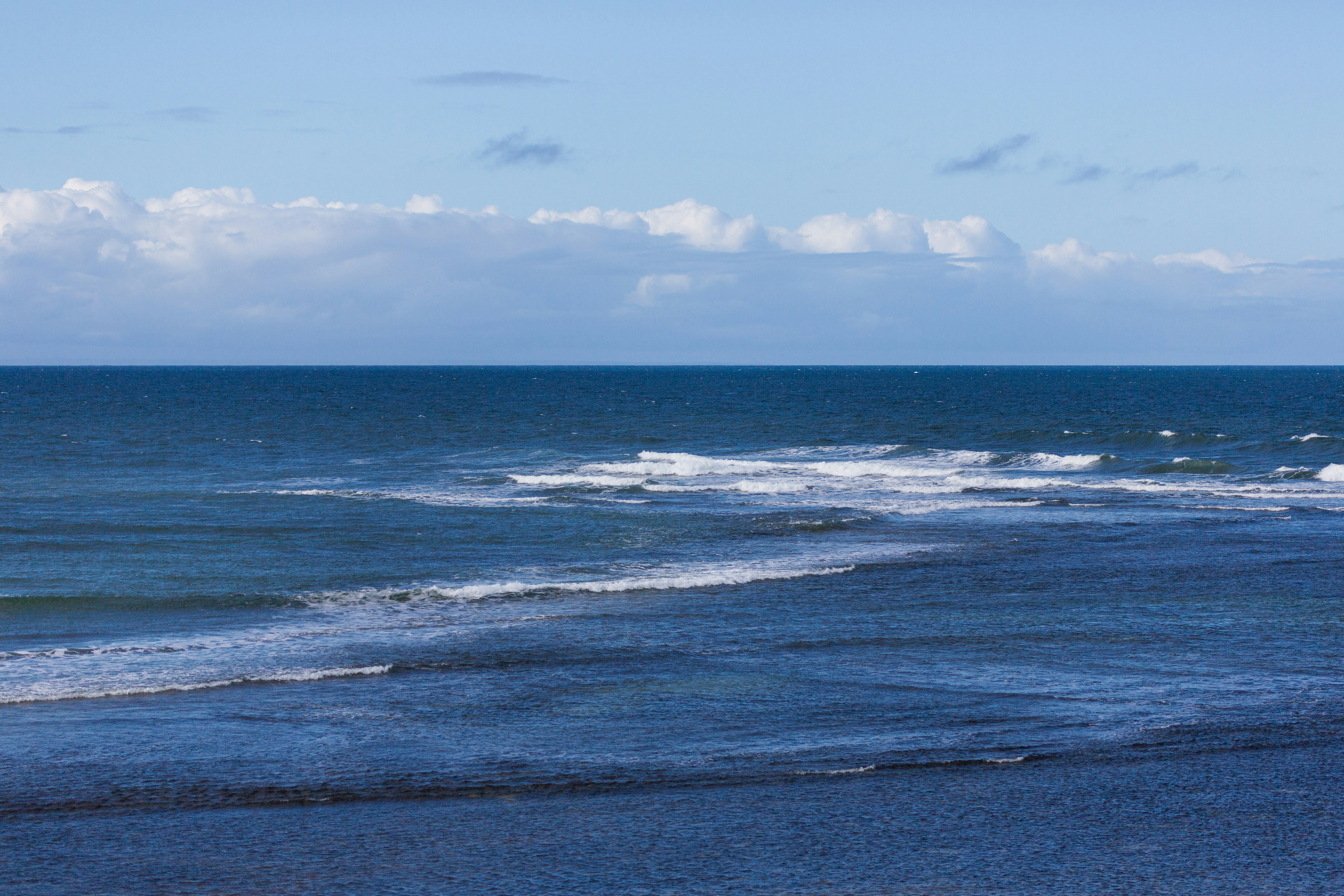 Waves gently rolling onto a dark beach underlit beach.
