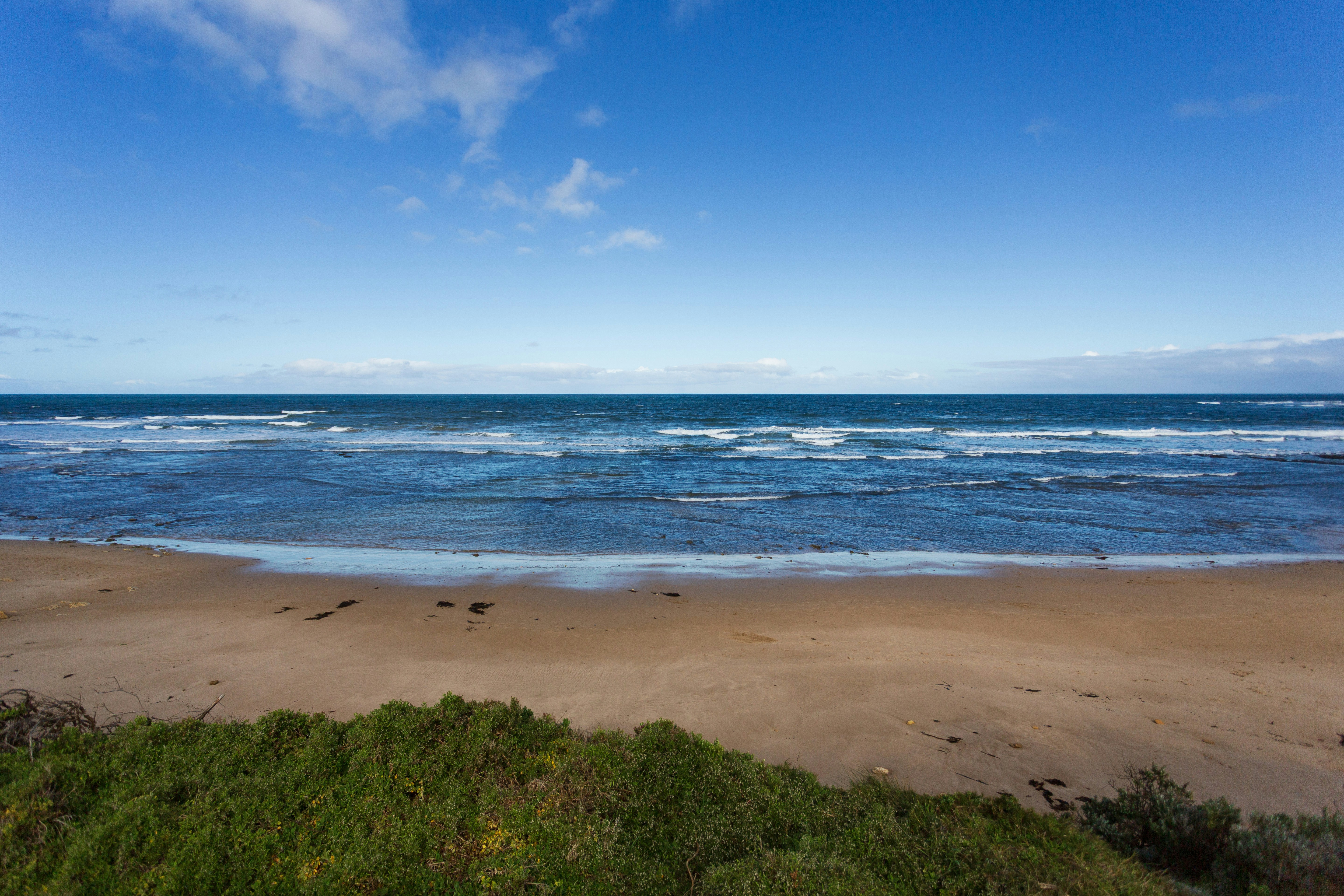 Waves crash on a sandy beach under a blue sky.