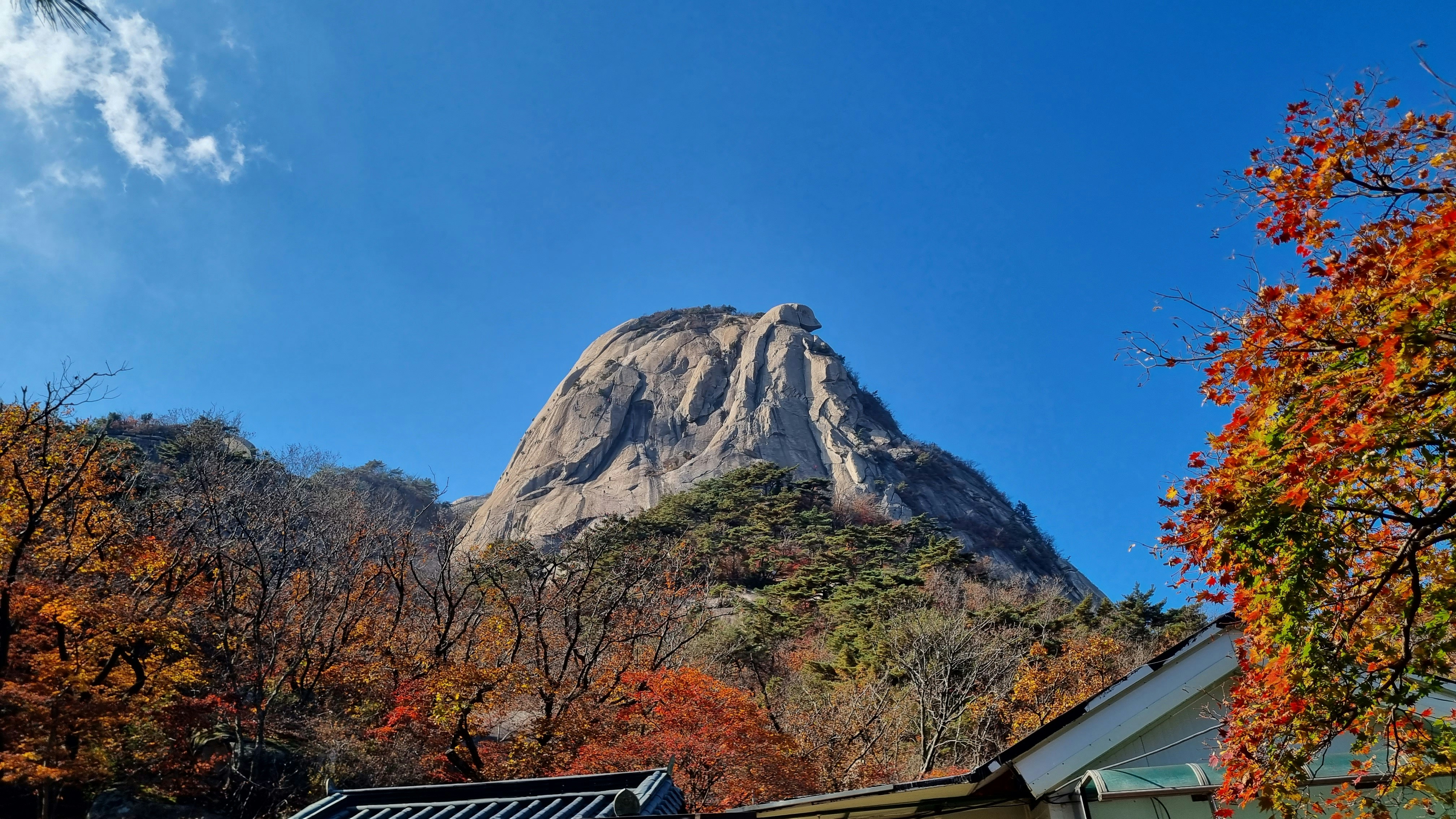 Large rock mountain with autumn trees and blue sky