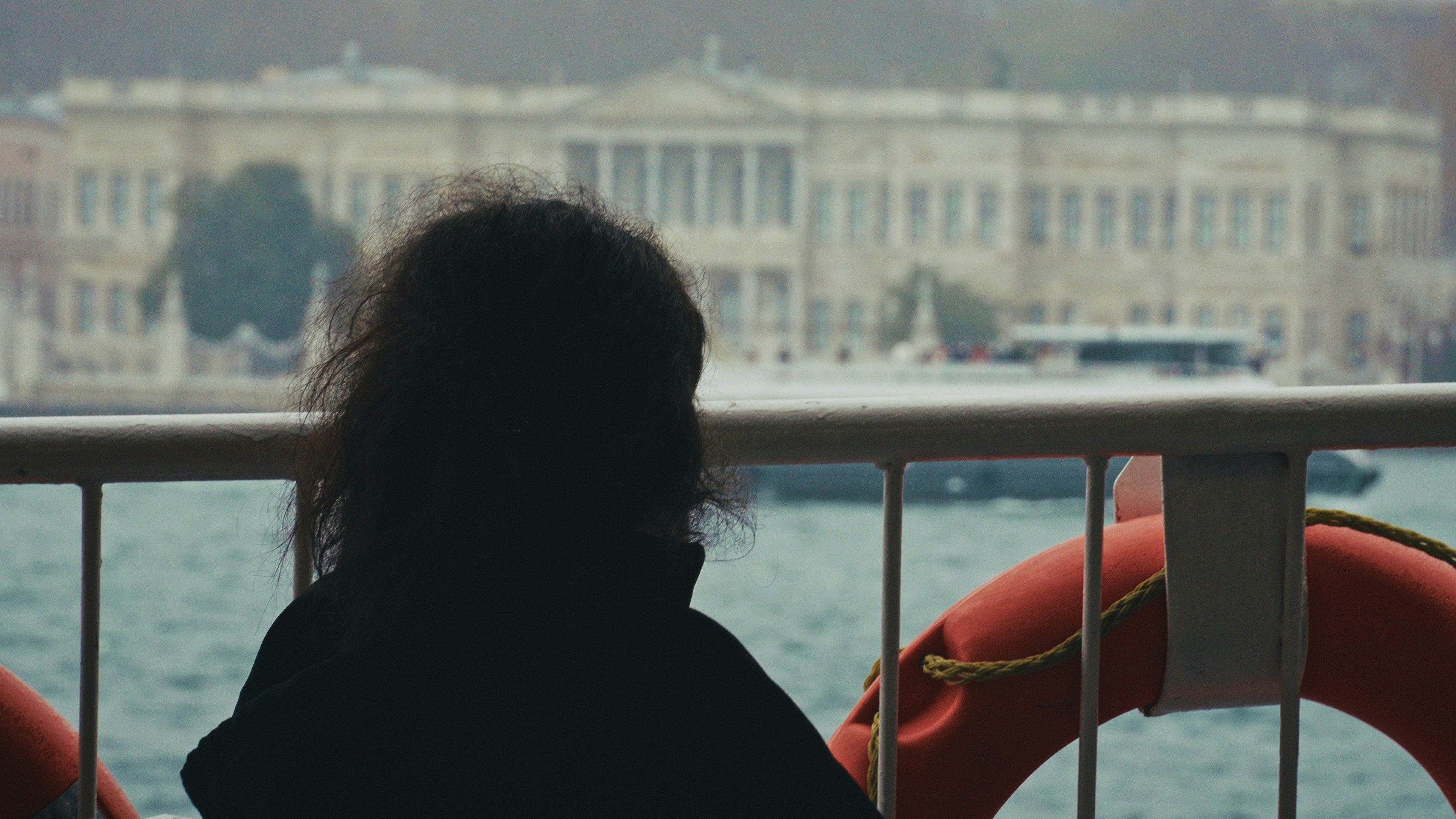 Person on ferry looking at grand building across water.