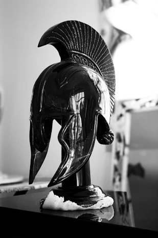 Black spartan helmet on a reflective surface.