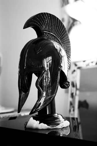 Black spartan helmet on a reflective surface.