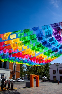 Colorful papel picado flags strung across a sunny plaza.