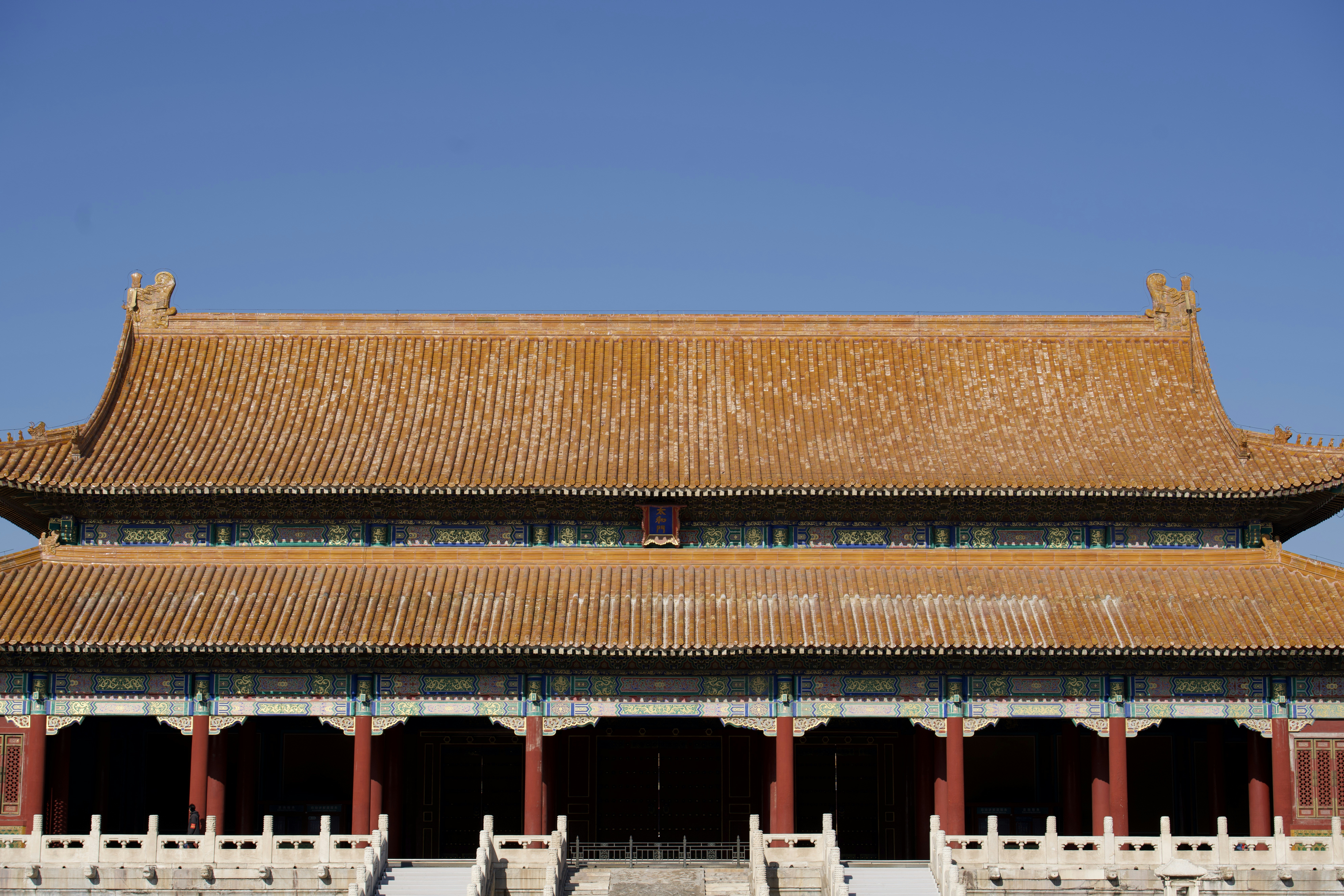 Traditional chinese palace roof under a clear blue sky.