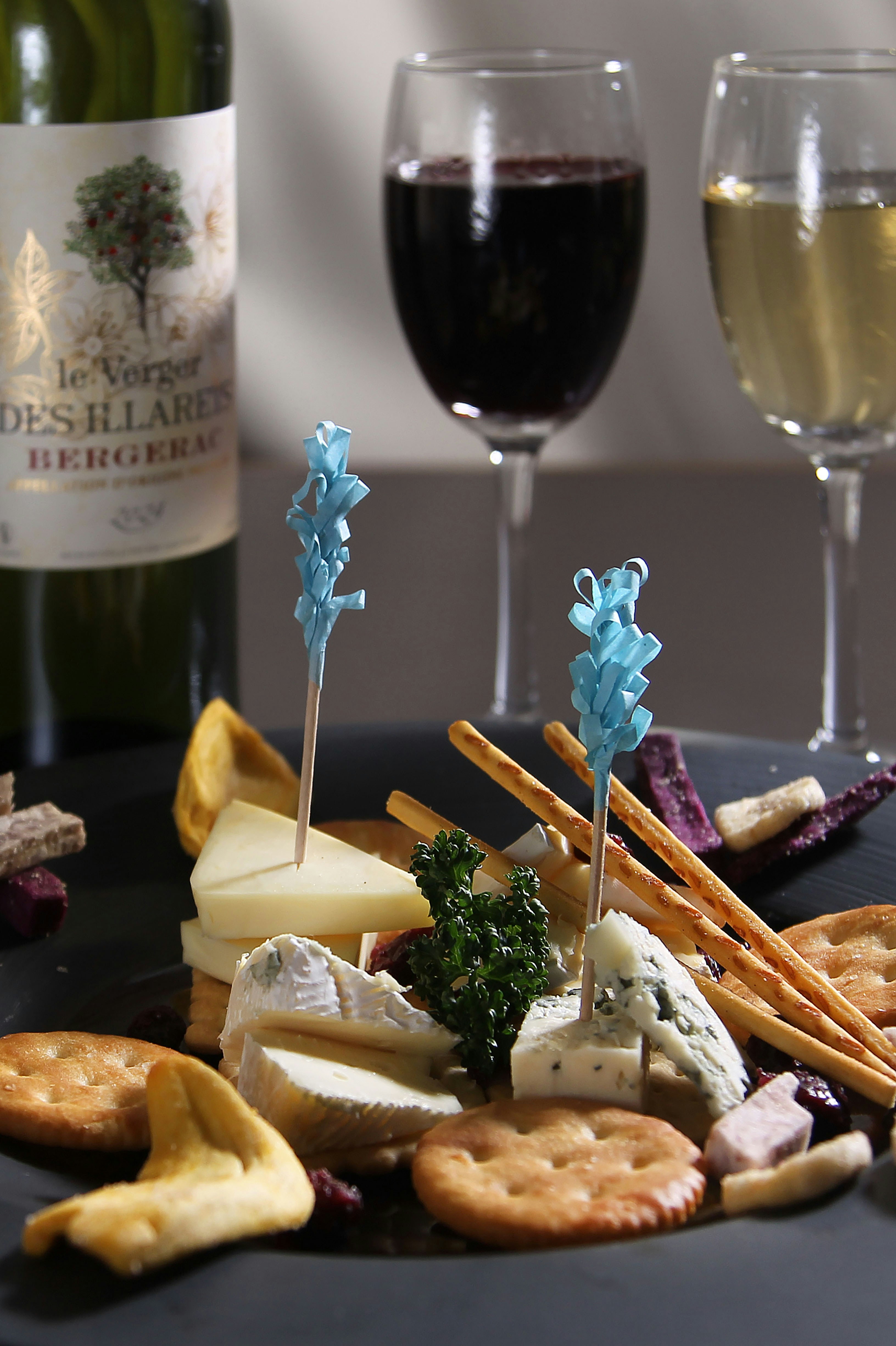 Cheese board with crackers, wine, and decorative picks.