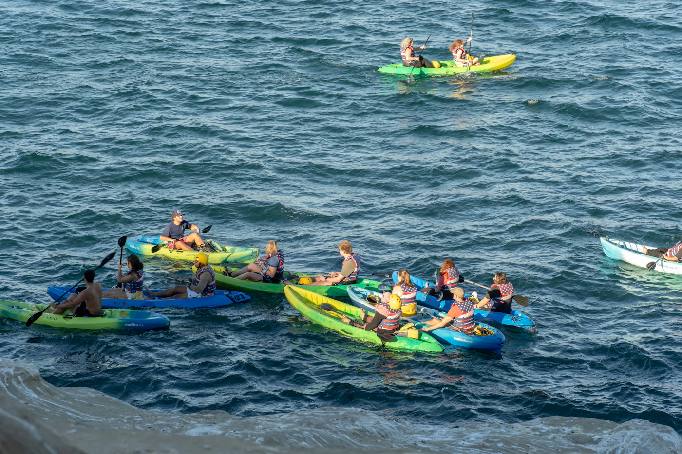 Kayakers moving across open coastal water