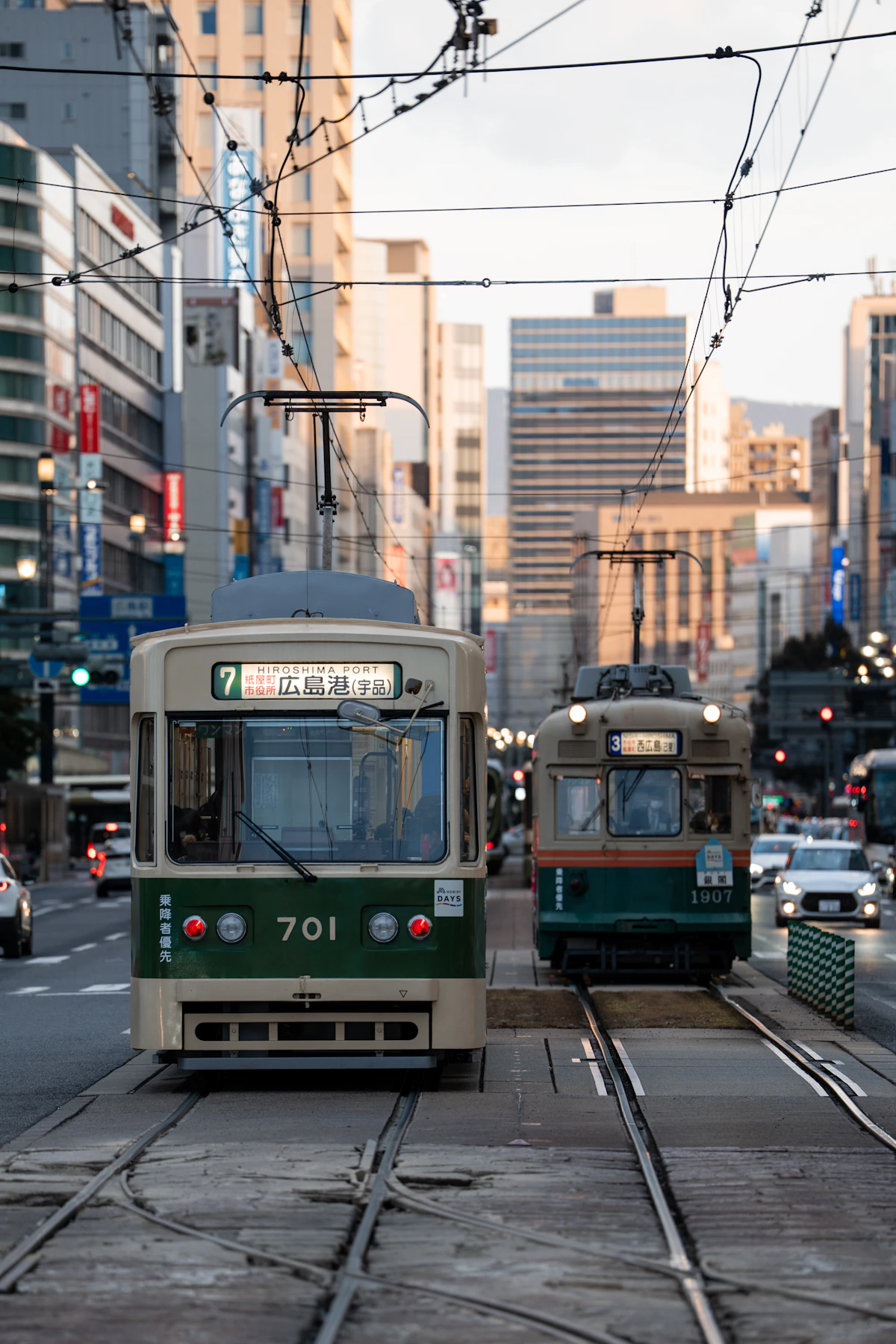 Two green and cream trams travelling through central Hiroshima