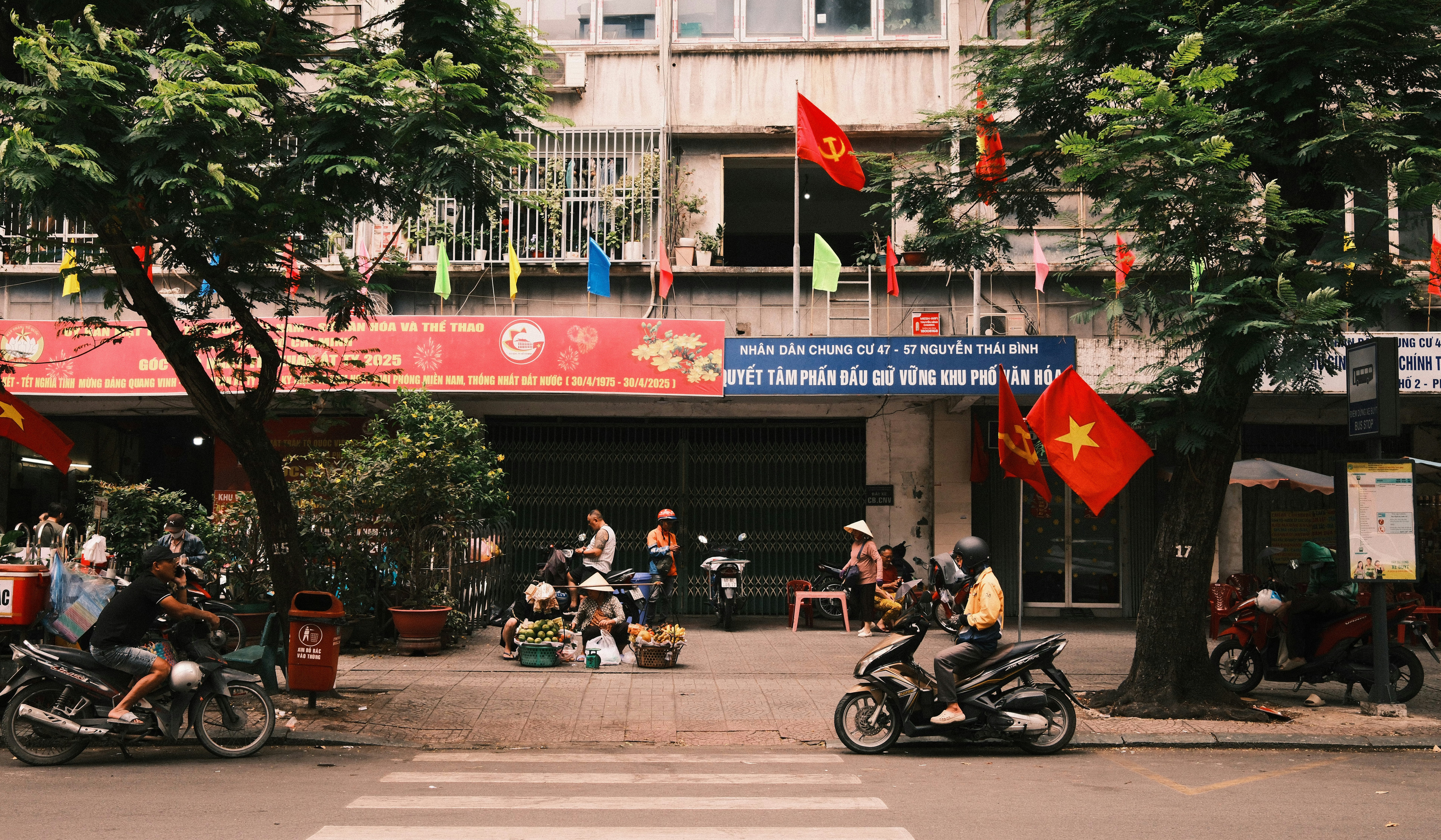 Motorbikes parked on a street with vietnamese flags.