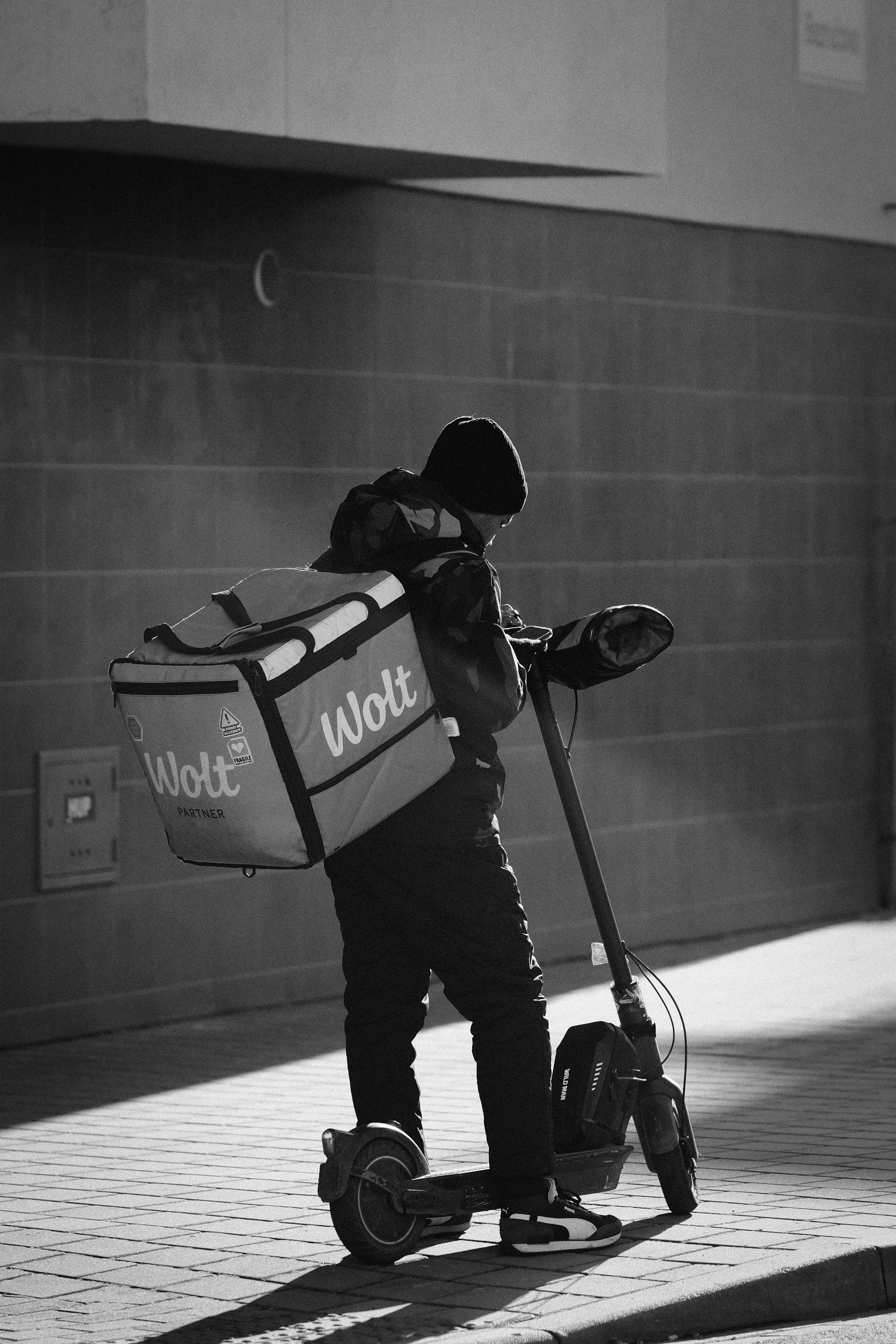 Delivery person with wolt bag on electric scooter