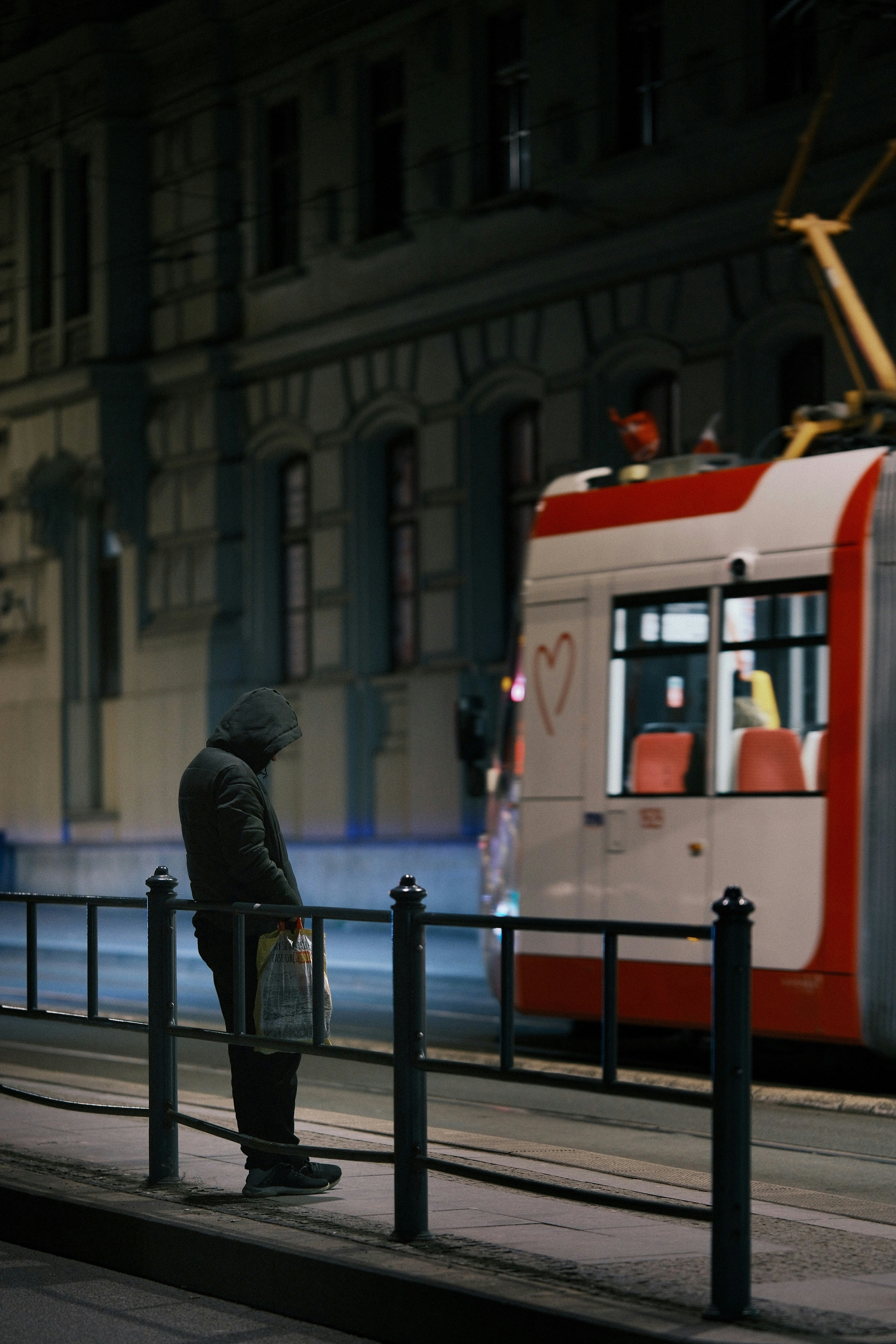 Person waits for tram at night with heart drawn