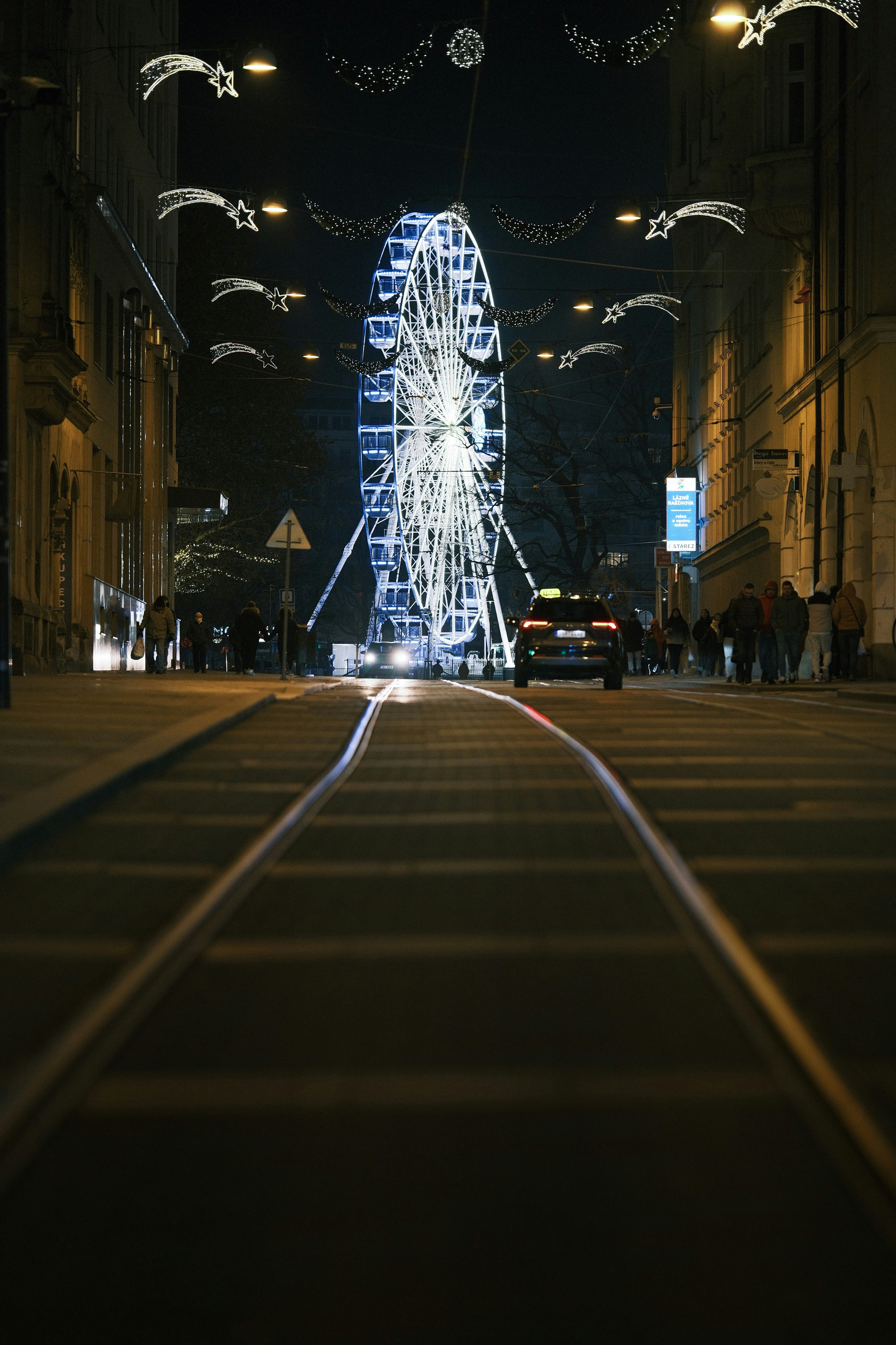 Ferris wheel lit up at night on city street