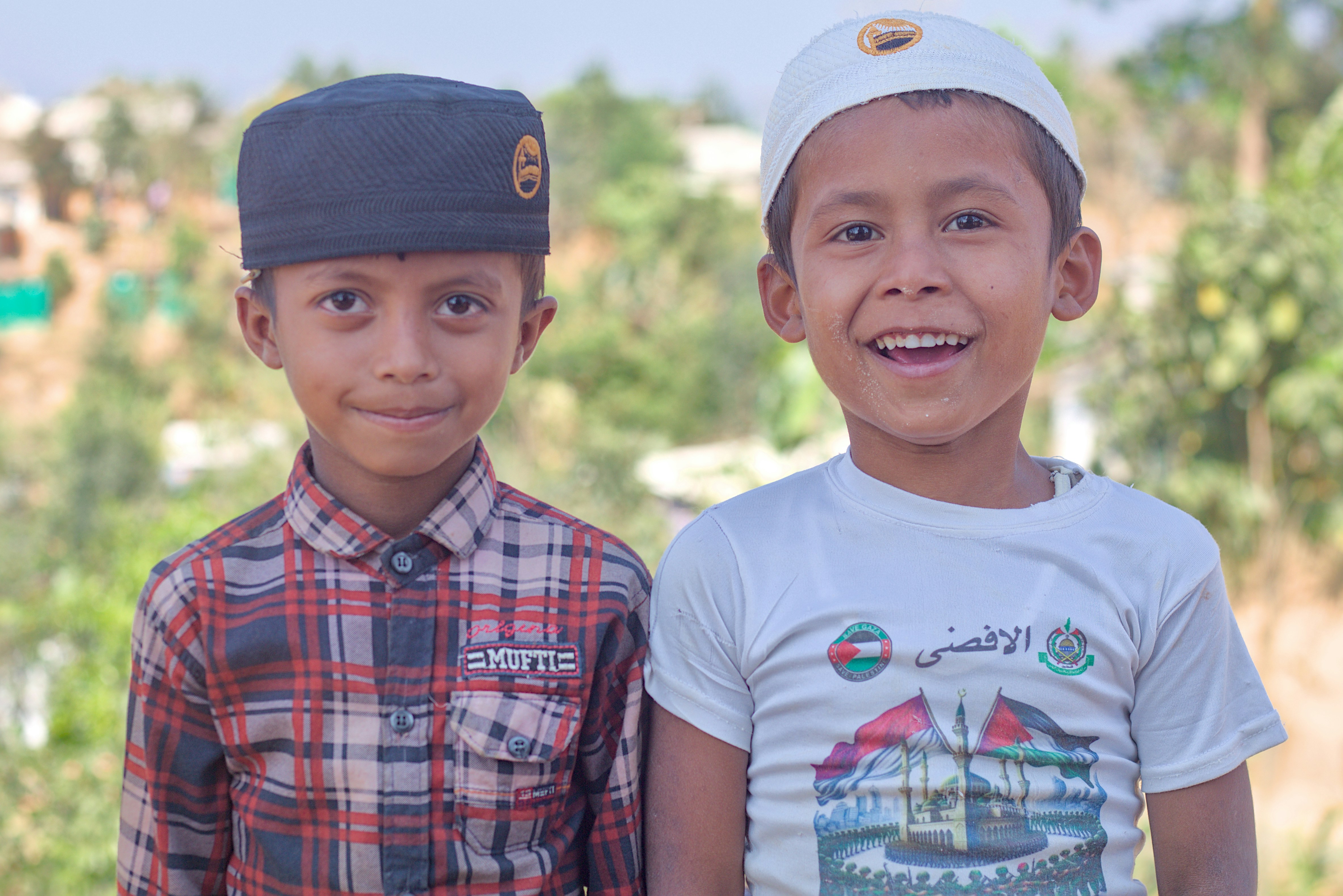 Two young boys wearing kufi hats smiling