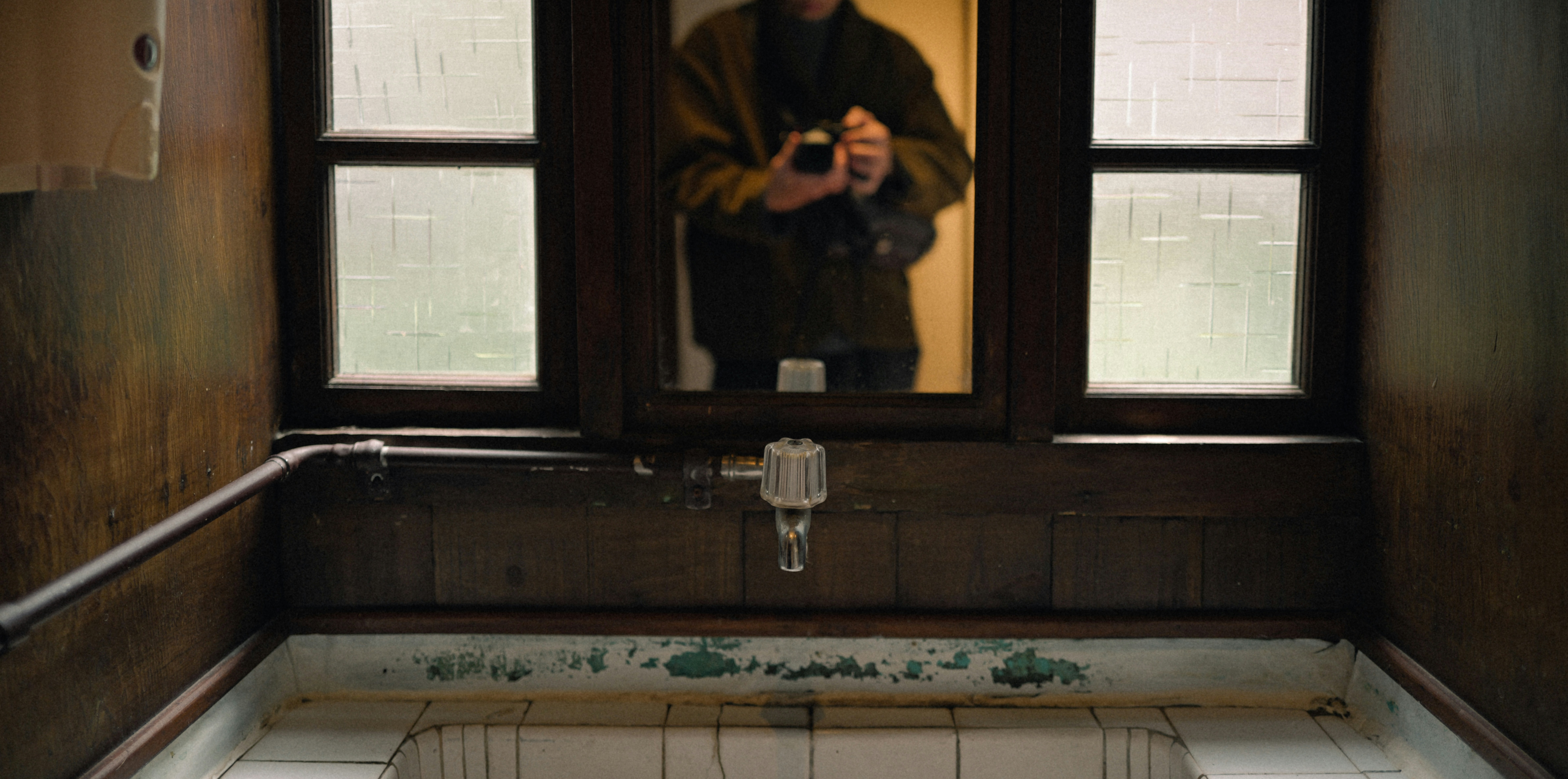 Person taking a selfie in a rustic bathroom.