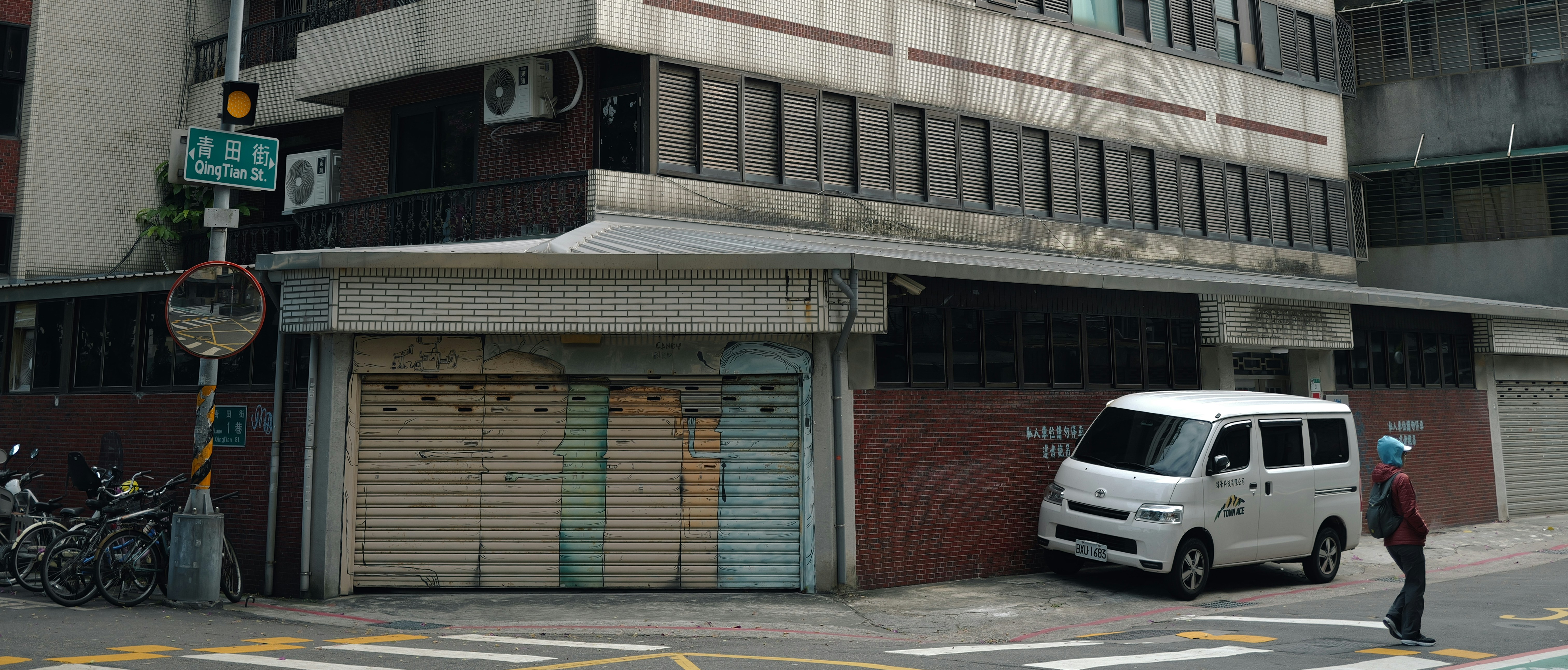 White van parked beside a building with closed shutters.