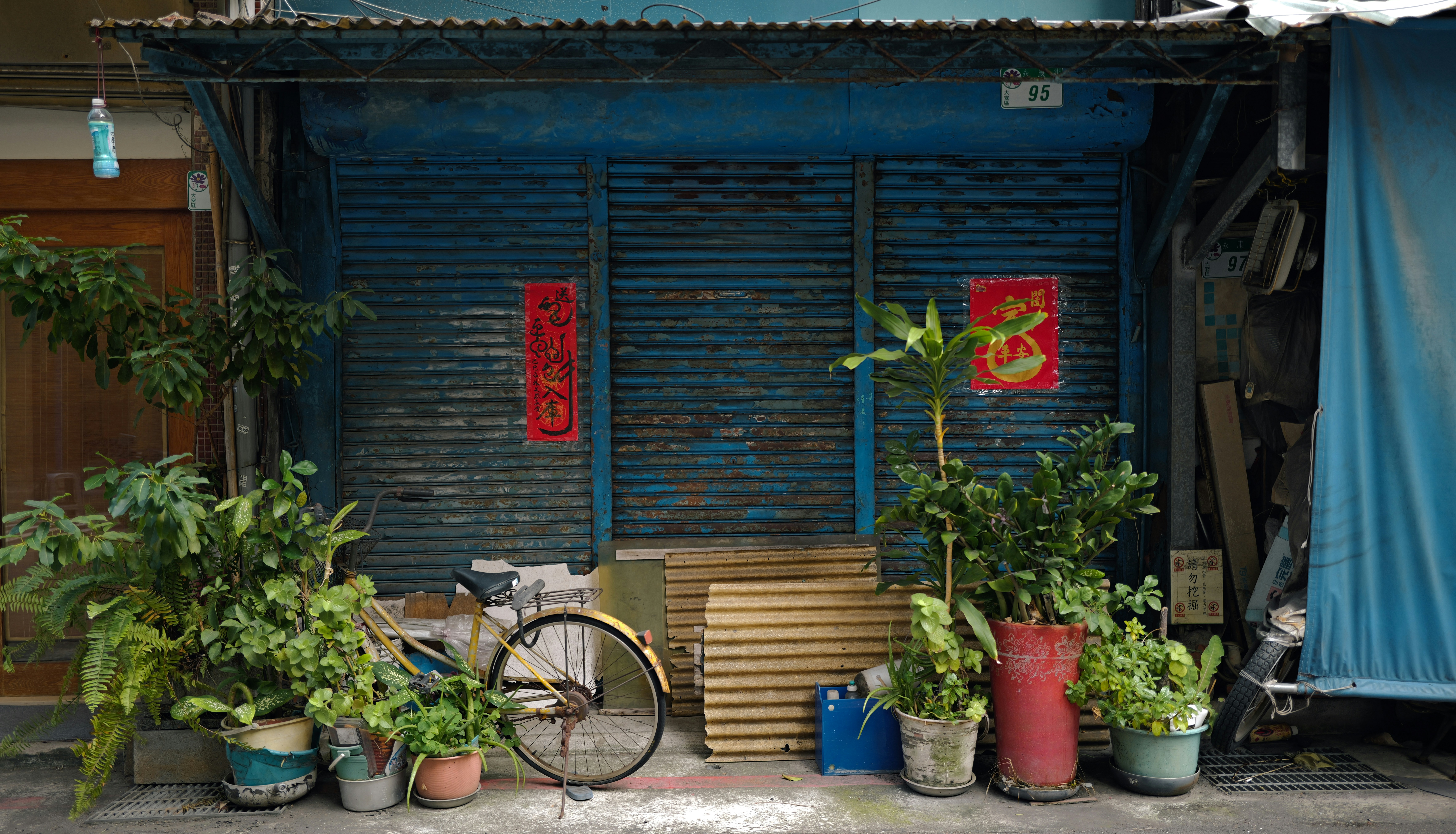 A vintage bicycle parked outside a blue shuttered shop.