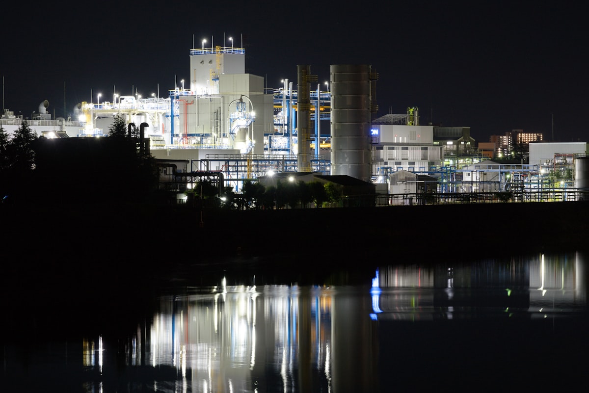 An industrial chemical facility illuminated at night with water reflection