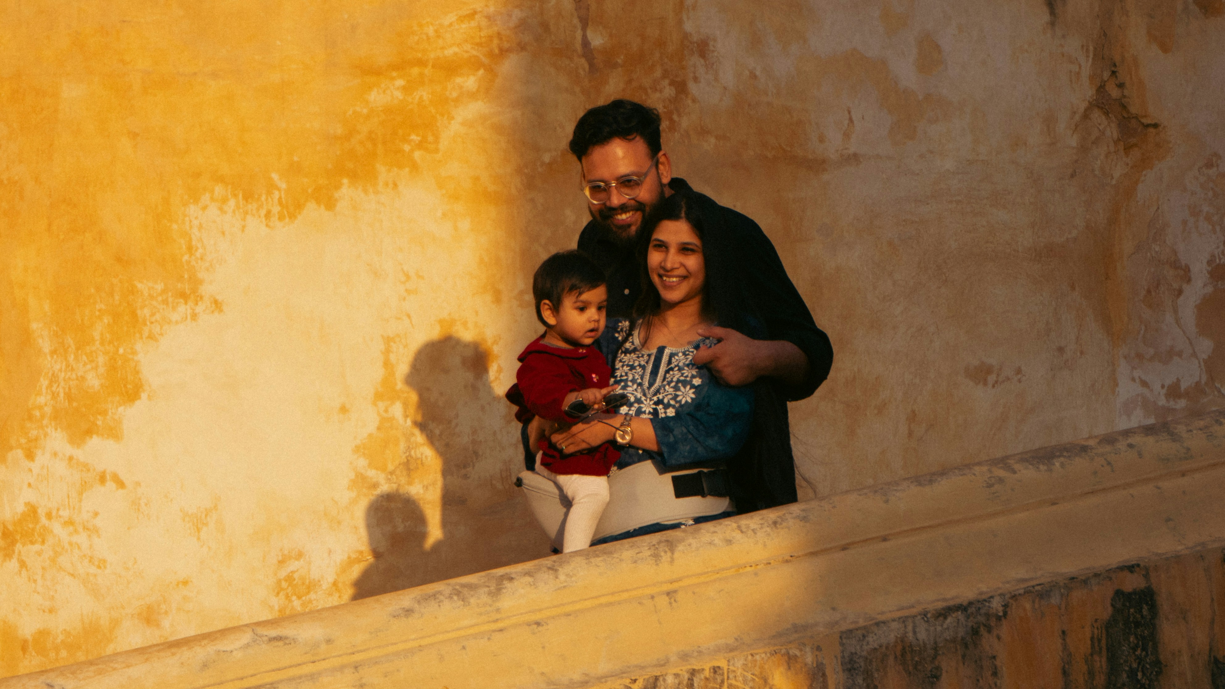 Une famille posant contre un mur jaune texturé.