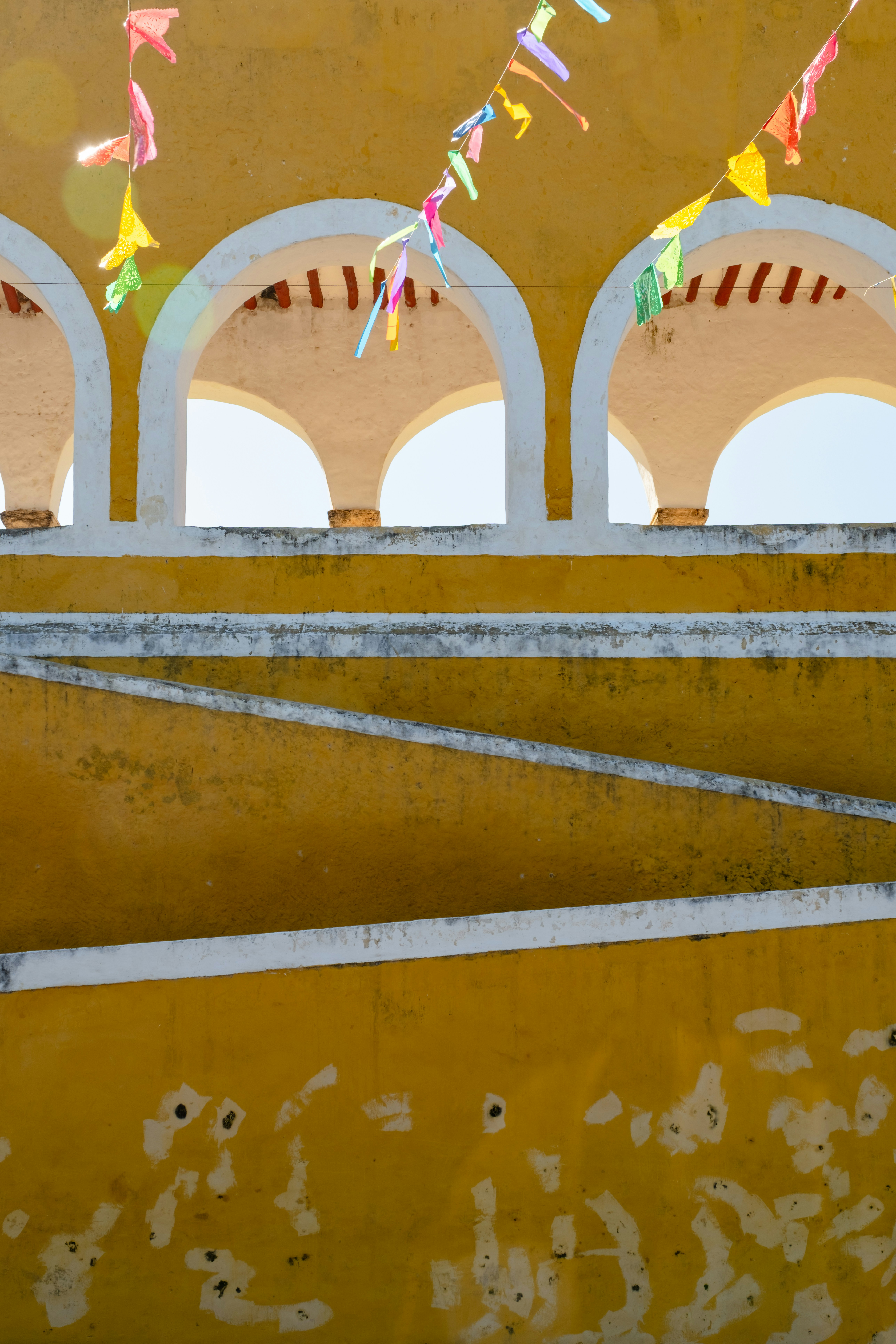 Yellow arches with colorful flags against a bright sky.