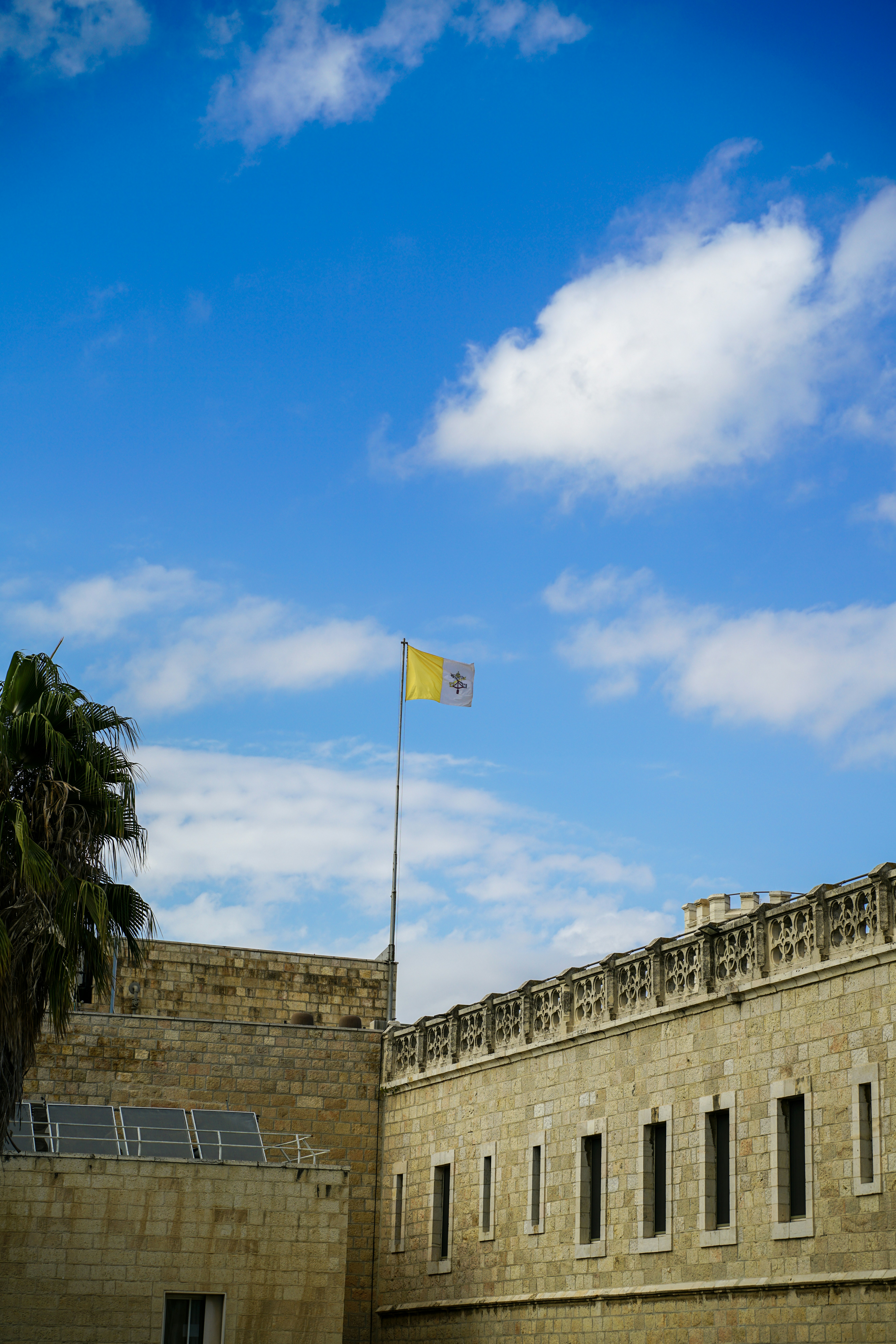Vatican flag flying over stone building under blue sky