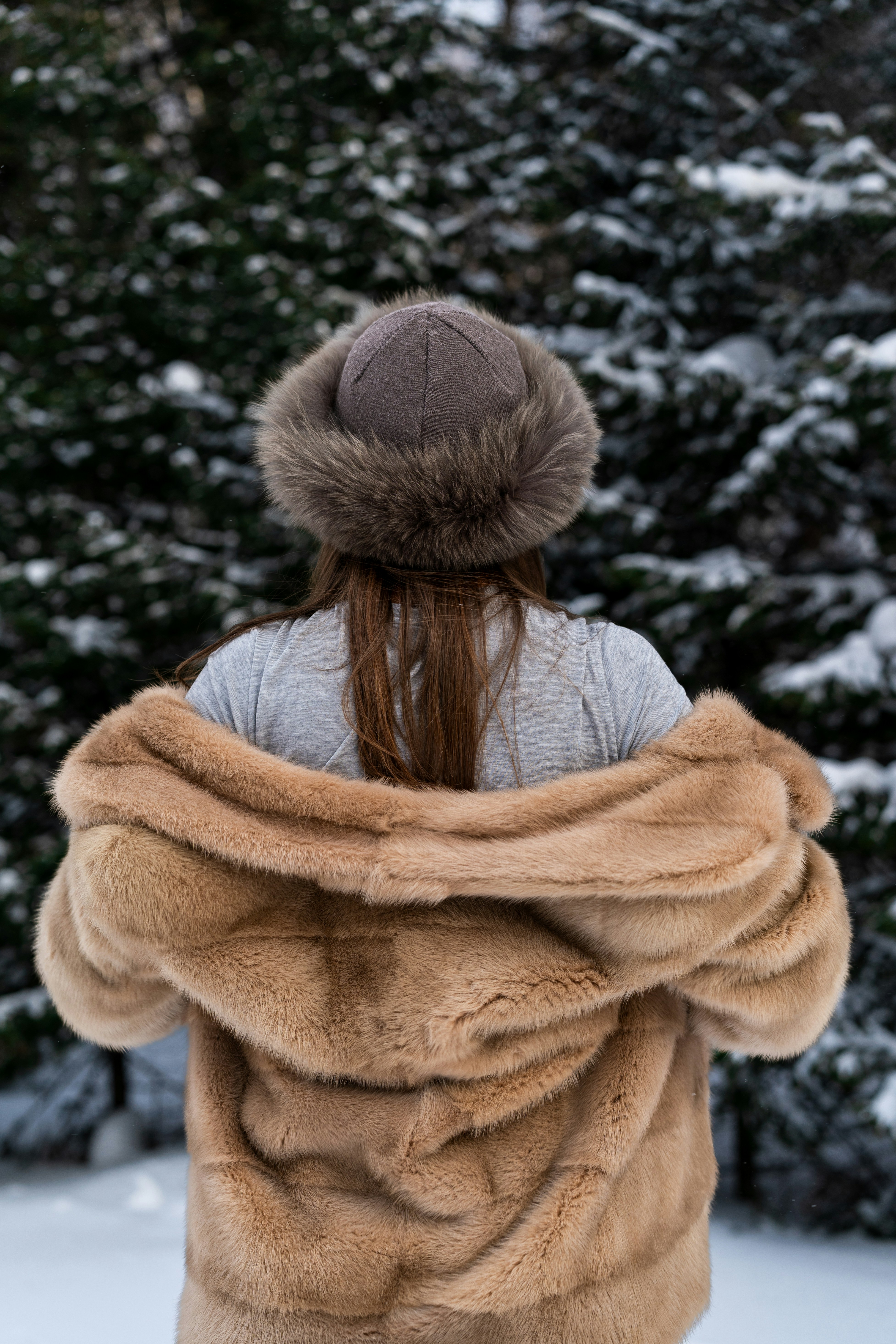 Woman in fur coat and hat in snowy forest.