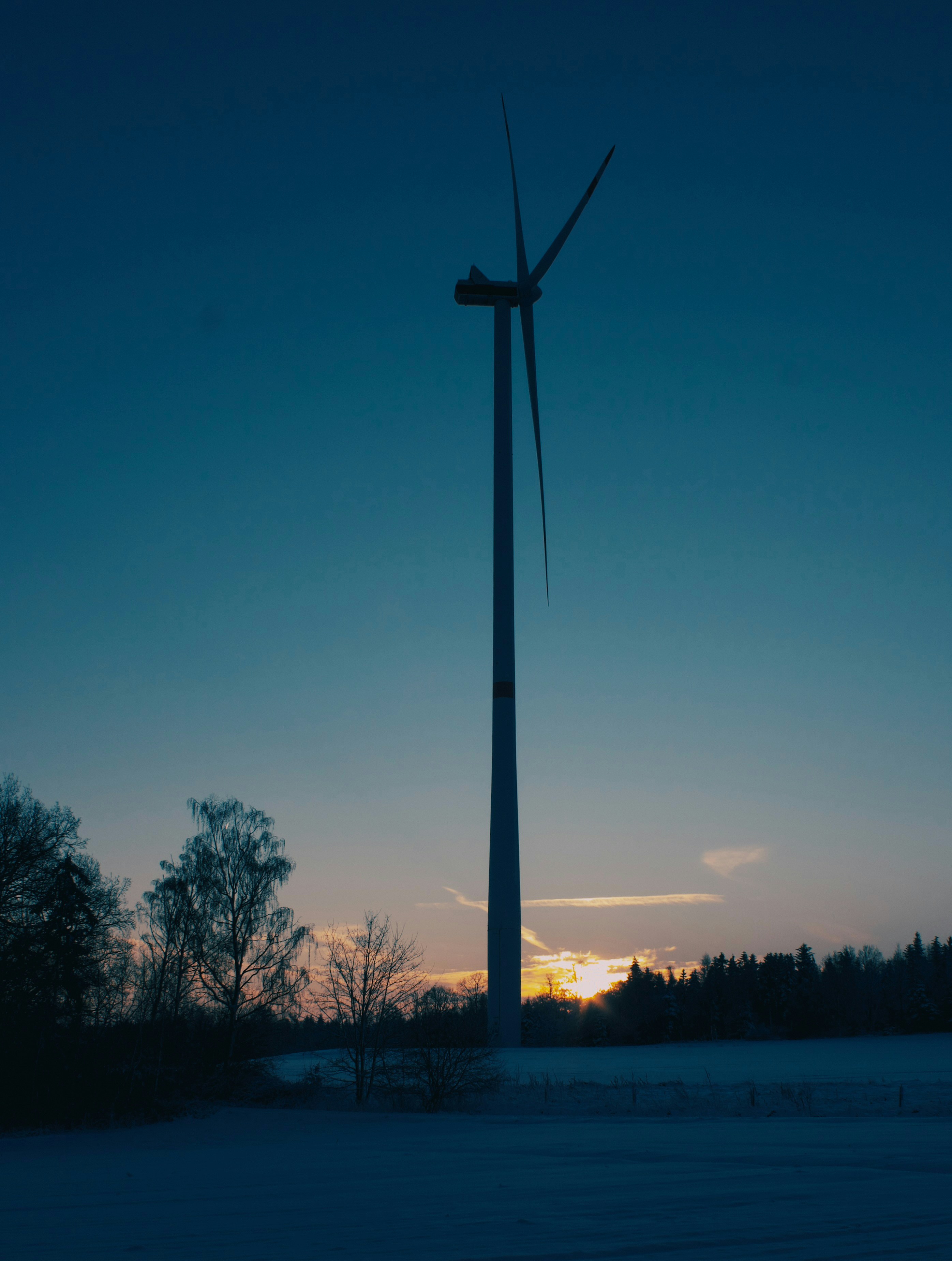一台の風力タービンが黄昏の空を背景に立っている。